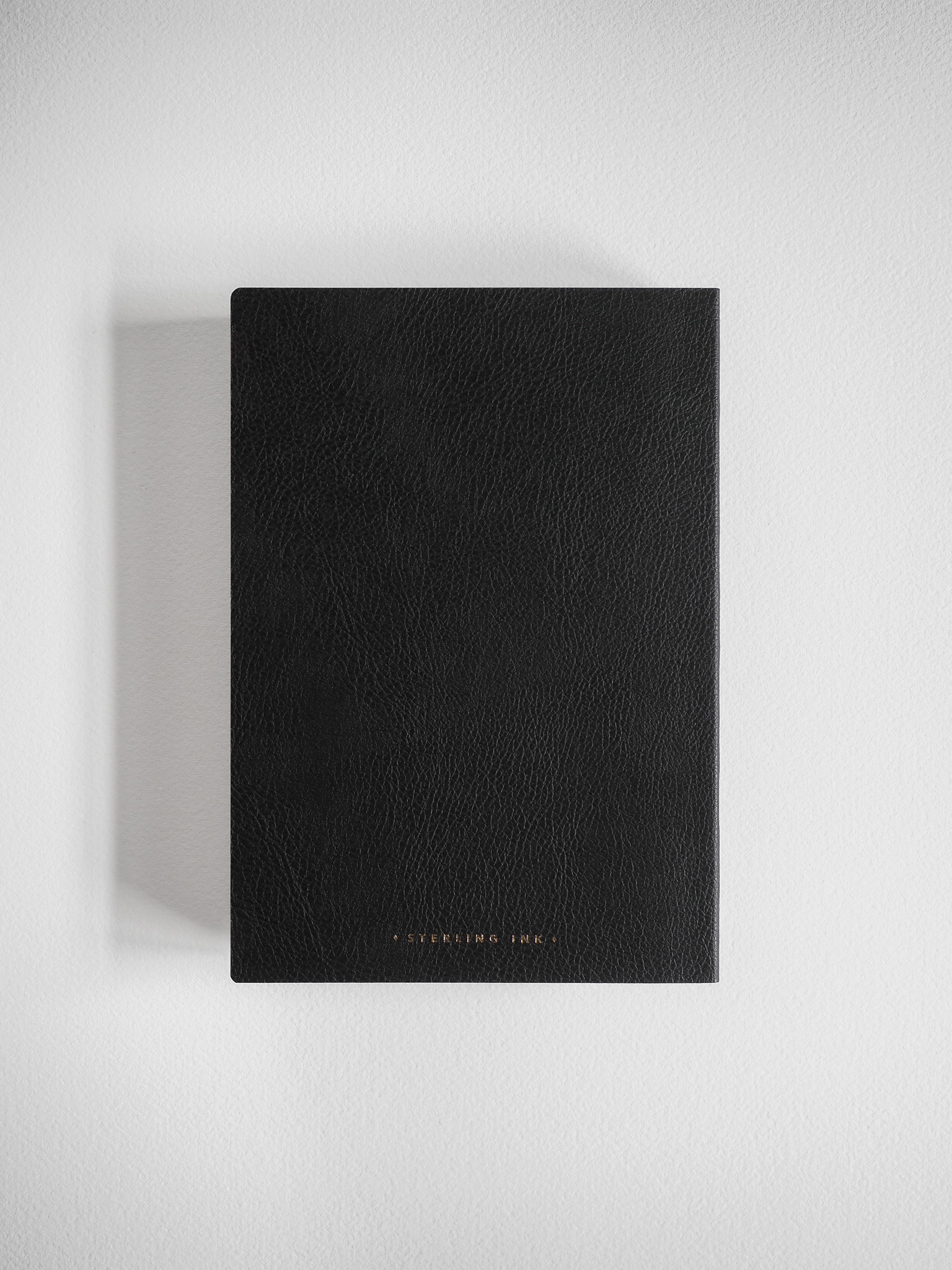 A minimalist B6 grid notebook featuring a sophisticated matte black cover and clean, centered "STERLING INK" branding for journaling and planning.