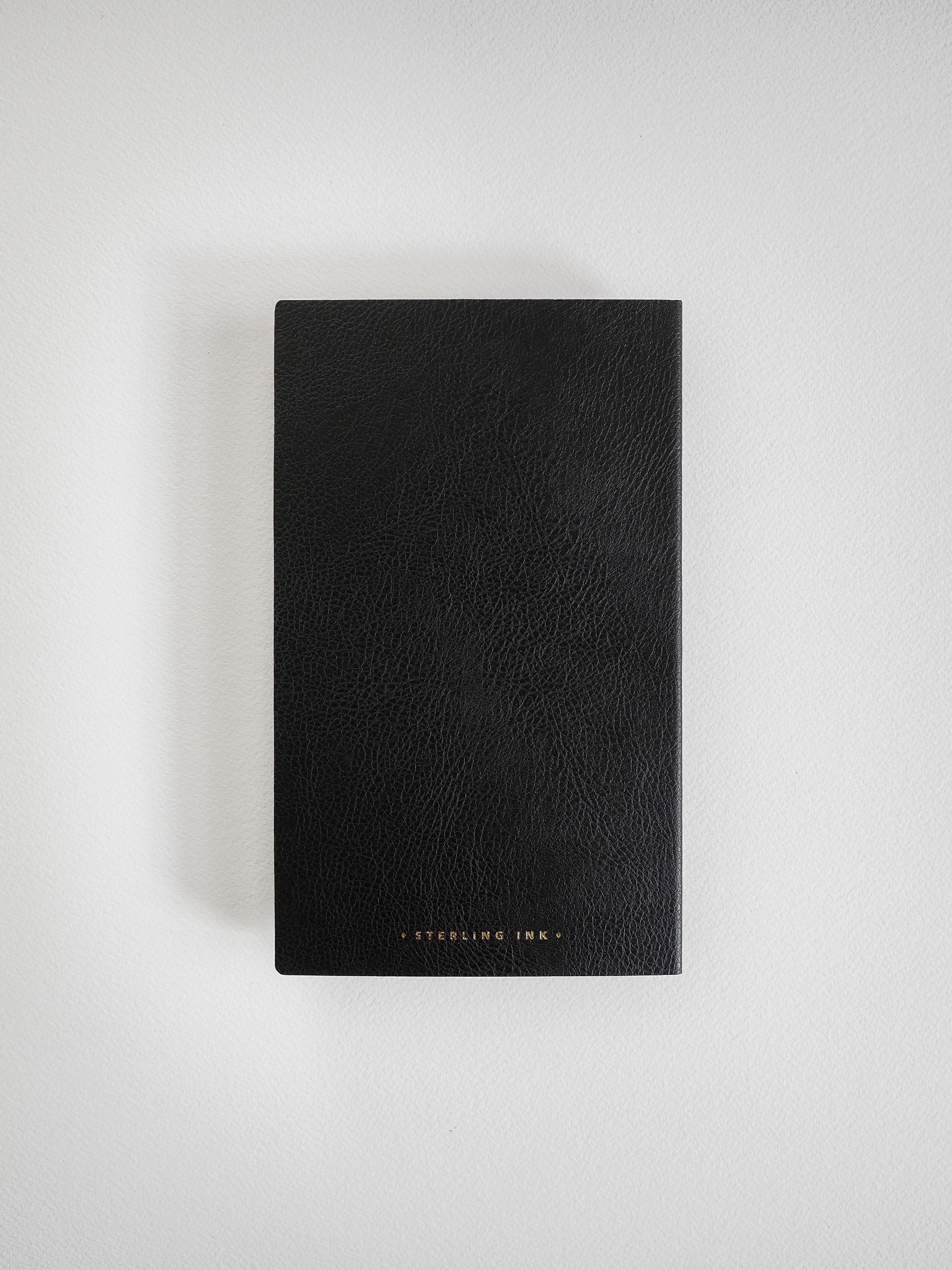A sleek, black B6 slim notebook featuring a textured cover and the "STEELING INK" logo subtly imprinted near the bottom edge.
