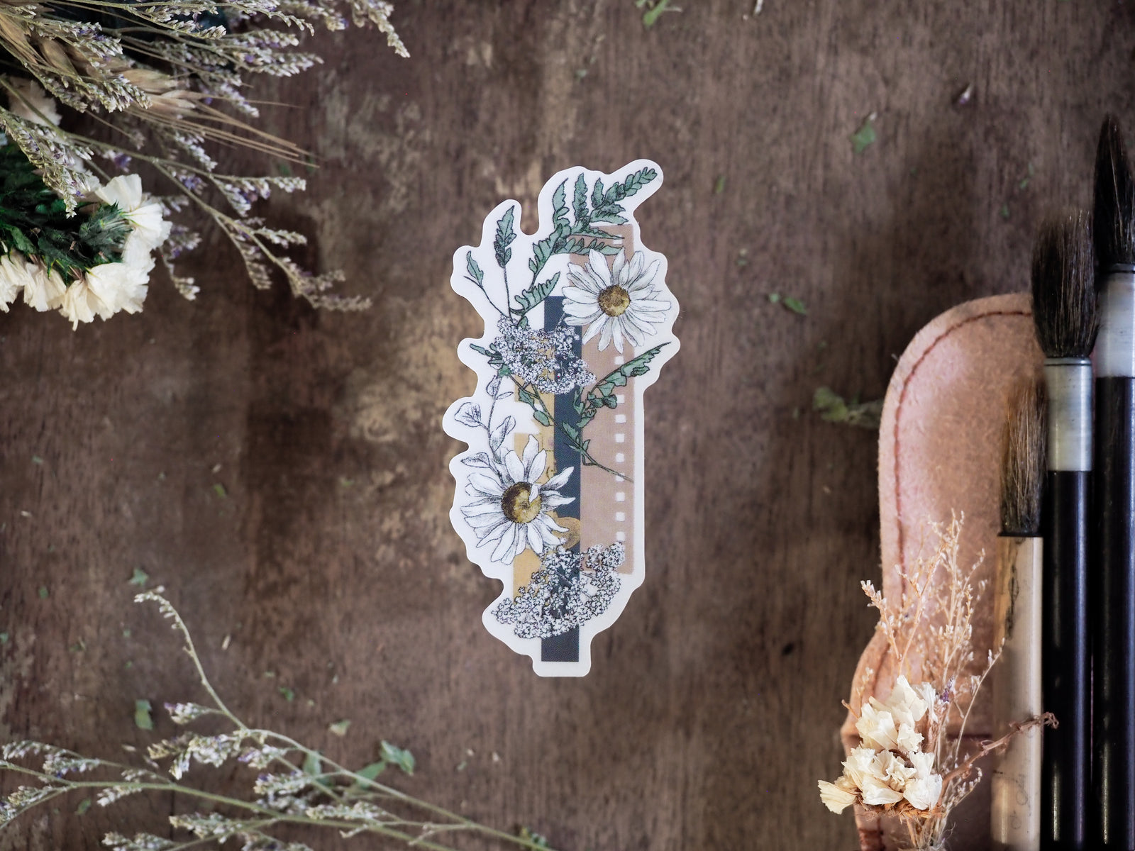 Decorative vinyl die-cut sticker featuring a botanical wreath of white daisies and green foliage alongside a vertical calendar strip for planning or journaling.