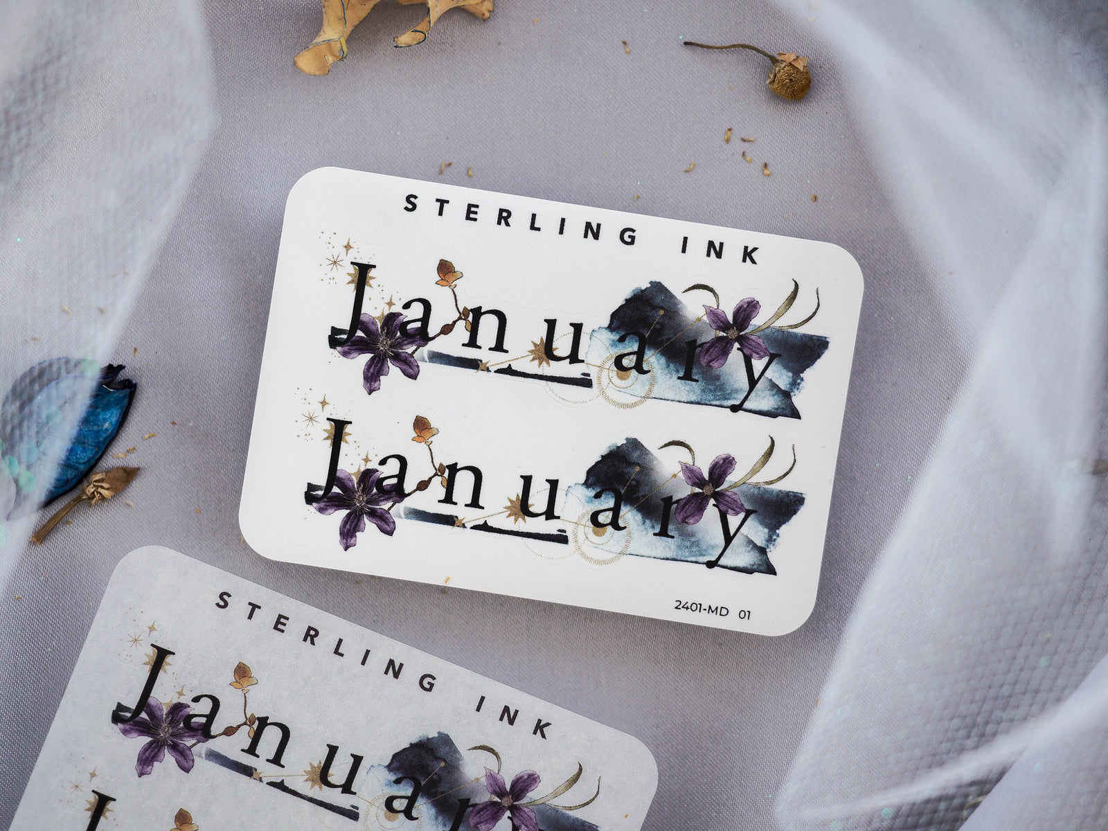 Stylish "January" month sticker printed with vibrant, deep purple and blue watercolor florals and clean black lettering.