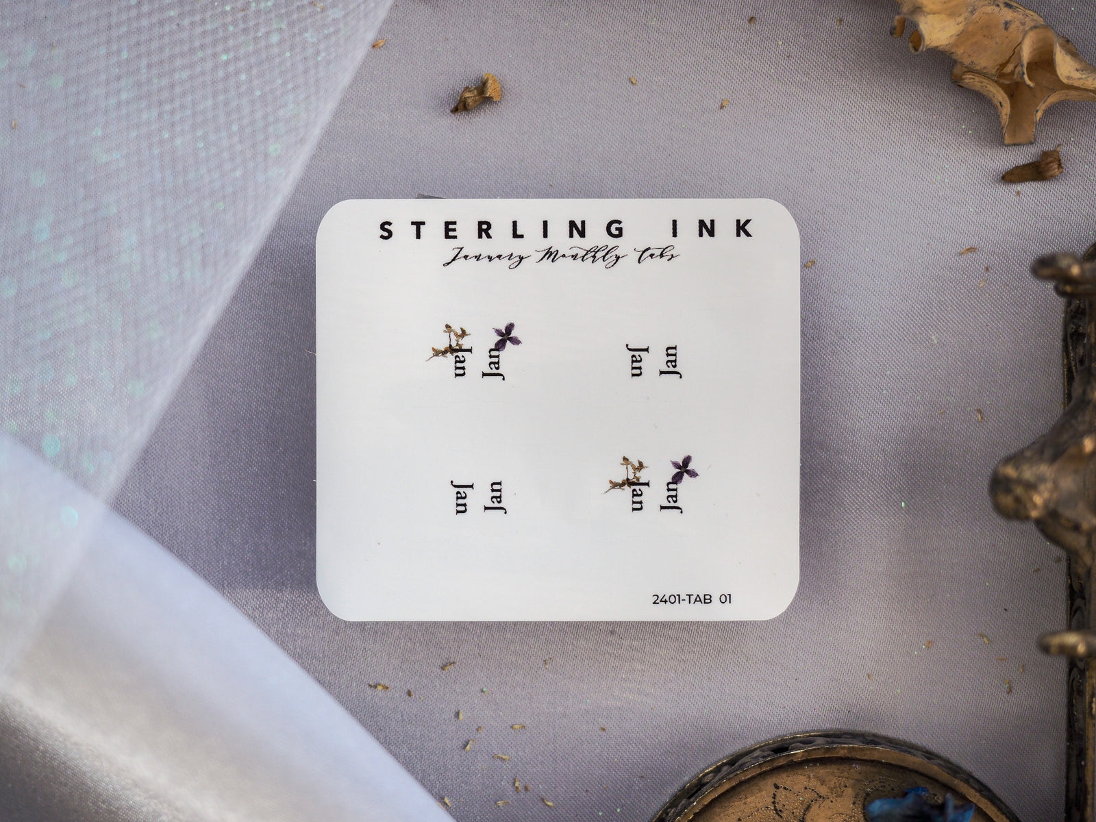 Delicate white planner tabs for January 2024, branded by Sterling Ink, featuring a romantic pattern of small printed birds and floral accents.