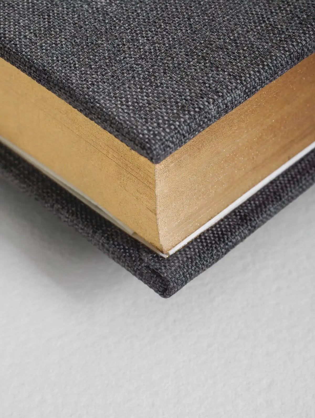 Close-up of a book with textured black cover and beige pages on a light gray background
#Color_Charcoal