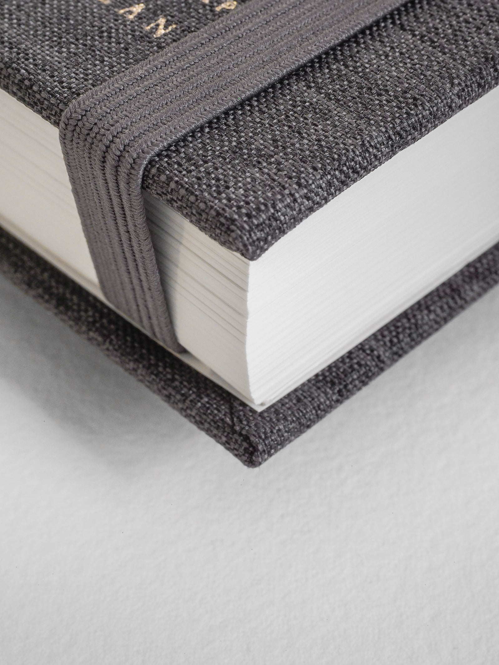 Close-up of a textured black book with white pages on a light gray background
#Color_Charocal