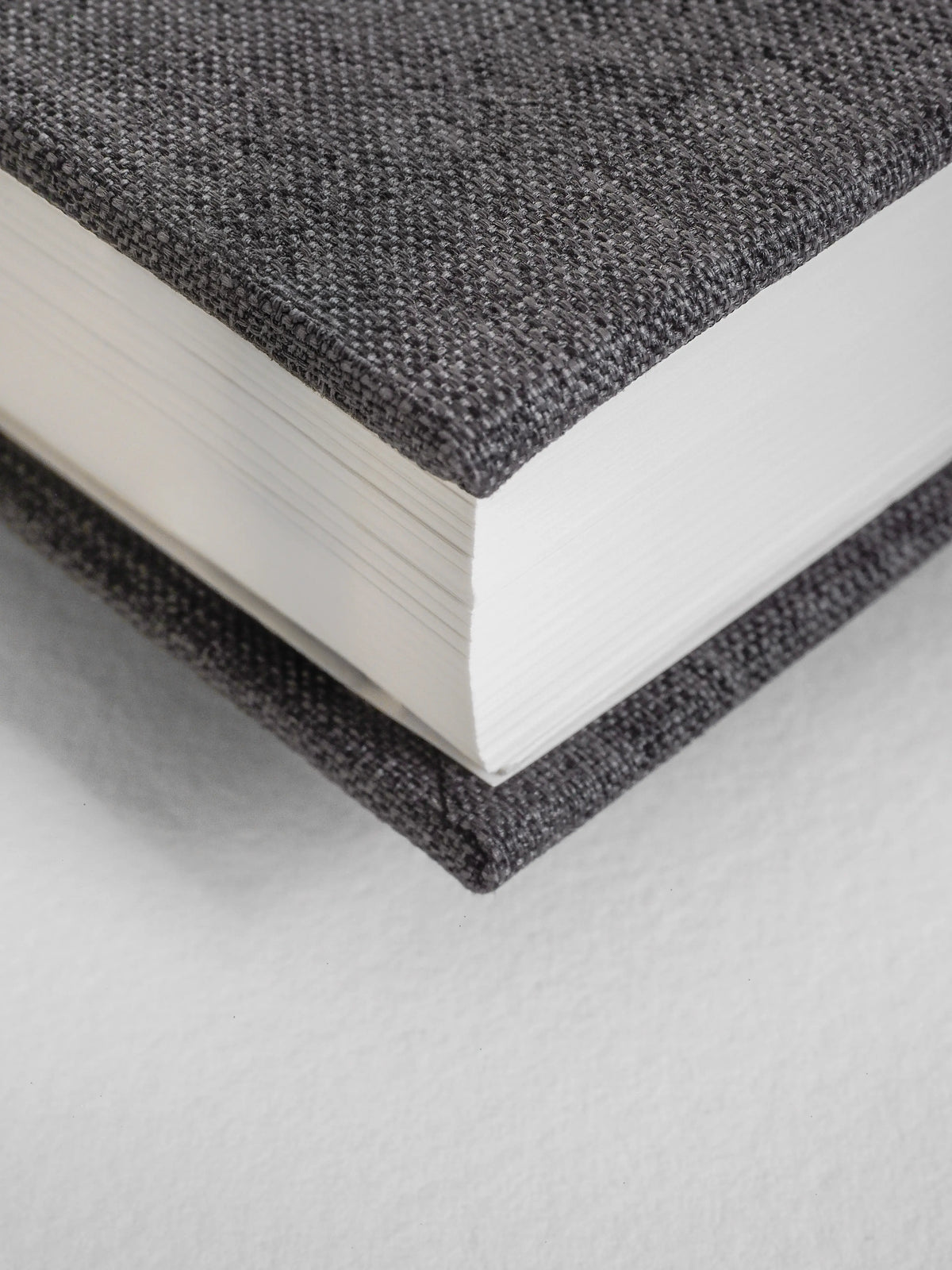 Close-up of a textured black book with white pages on a light gray background
#Color_Charcoal