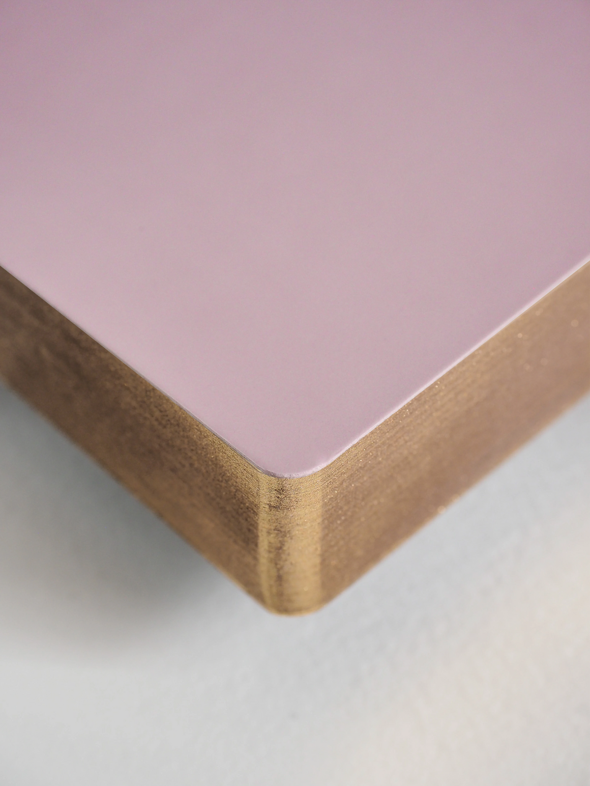 Close-up of a corner where a pink surface meets a wooden edge on a light gray background.
#Color_Fairyfloss