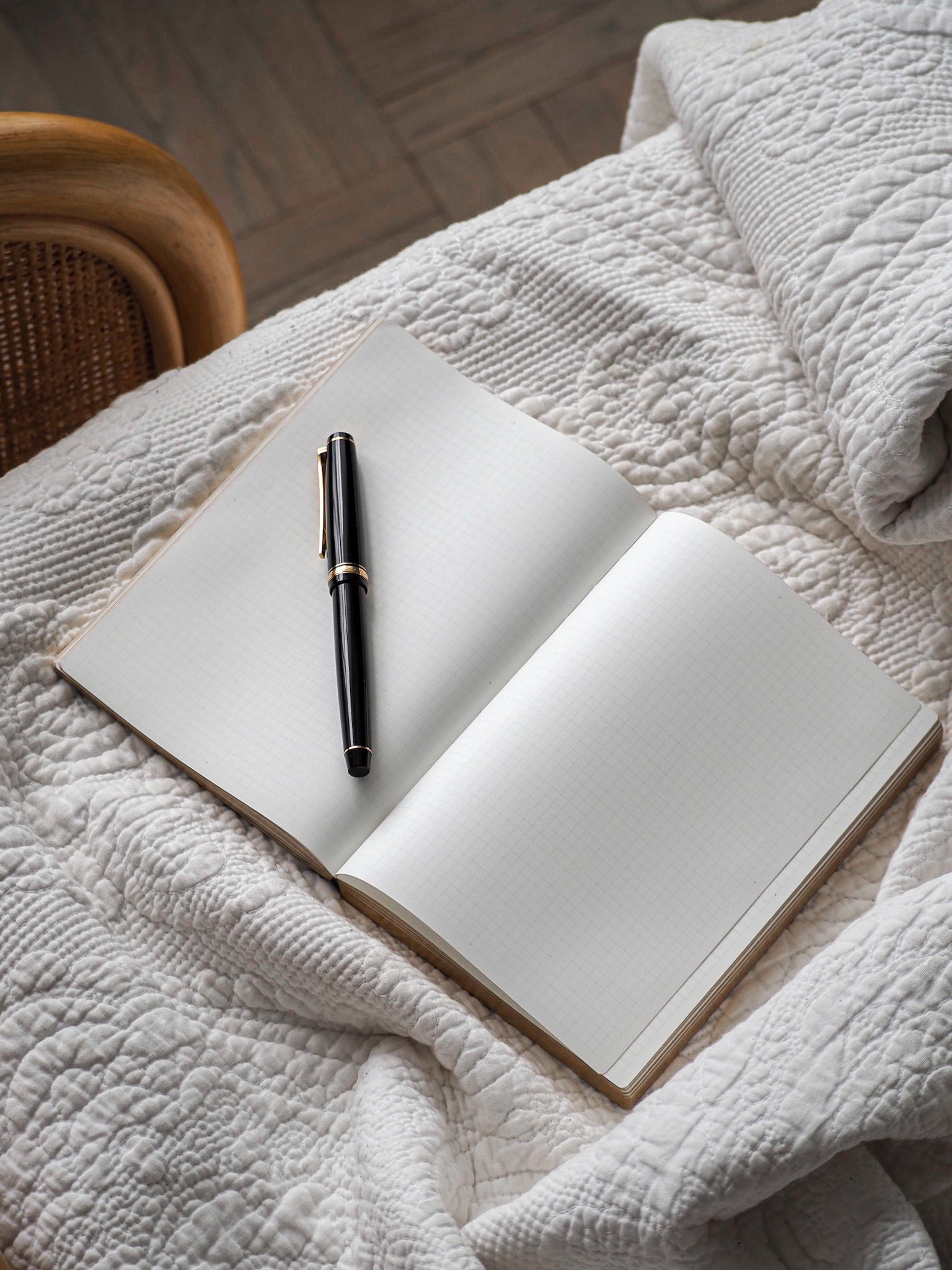 Open A6 grid notebook revealing structured, gridded white pages and natural wood-edged binding for journaling or planning.