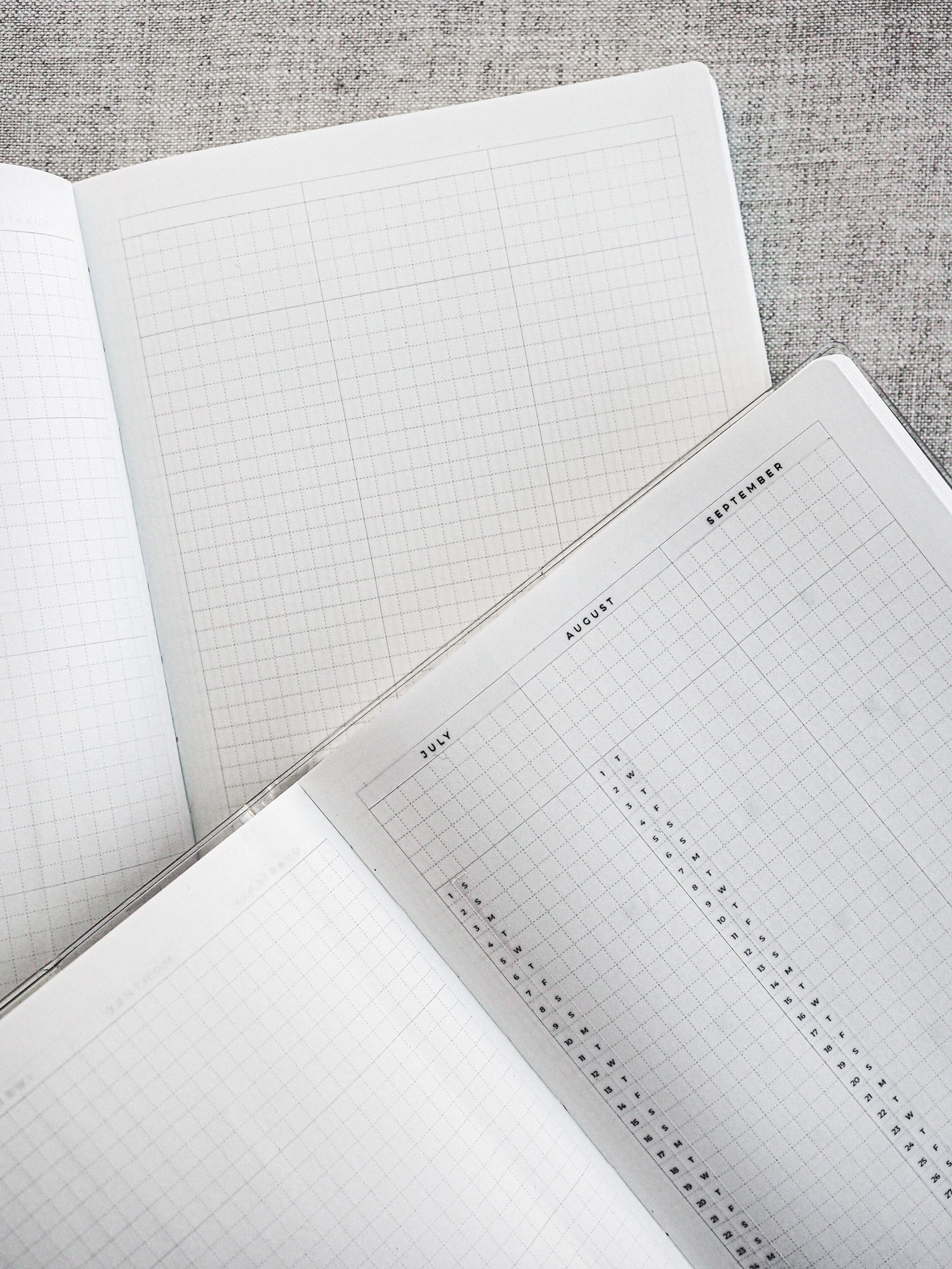 Open planner pages displaying quarterly layouts for July, August, and September, featuring detailed graph grids and designated months for seasonal planning.