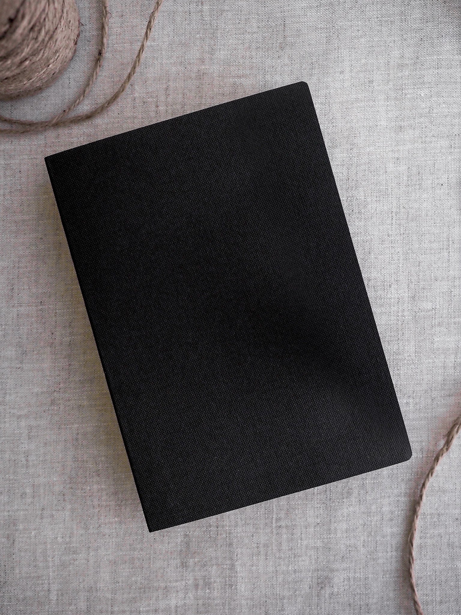 Sleek, solid black passport-sized notebook cover, featuring a minimalist design ideal for travel journaling or structured grid note-taking.