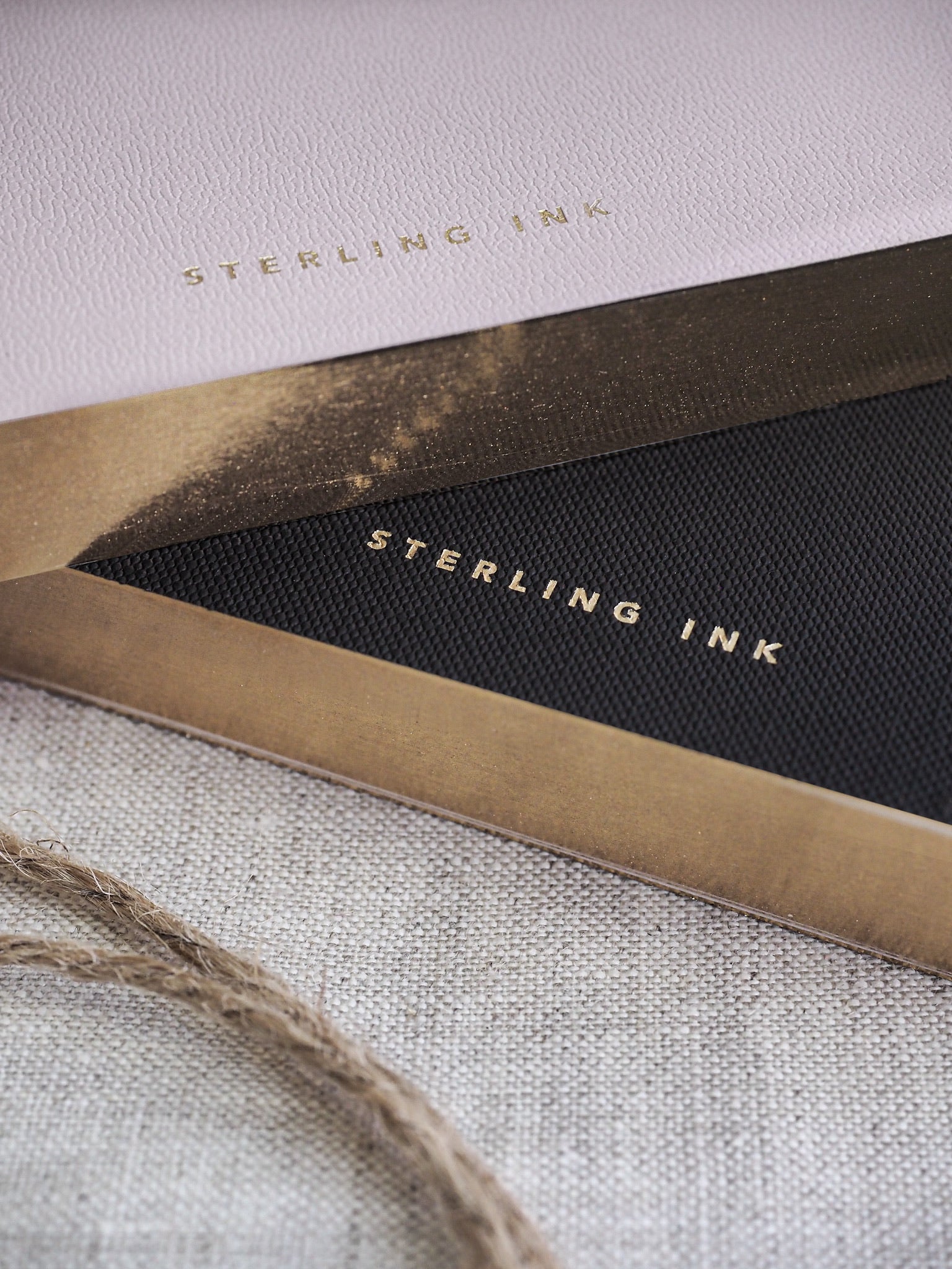 Minimalist A6 notebook featuring gold foil branding that reads "Sterling Ink," displayed on contrasting light and dark covers.