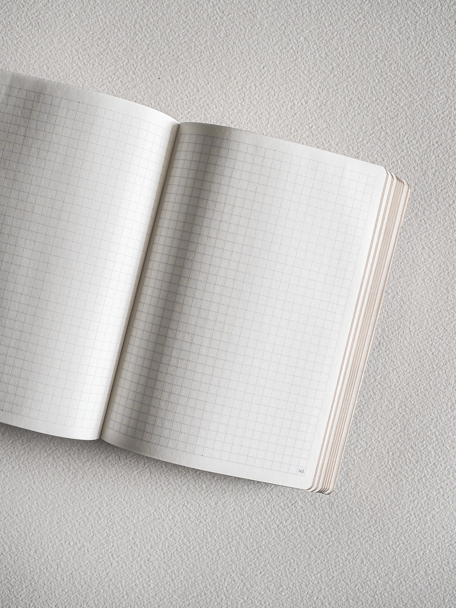 Open A6 grid notebook showing pristine white pages with a faint graph paper grid, ideal for organized journaling, study, or detailed note-taking.