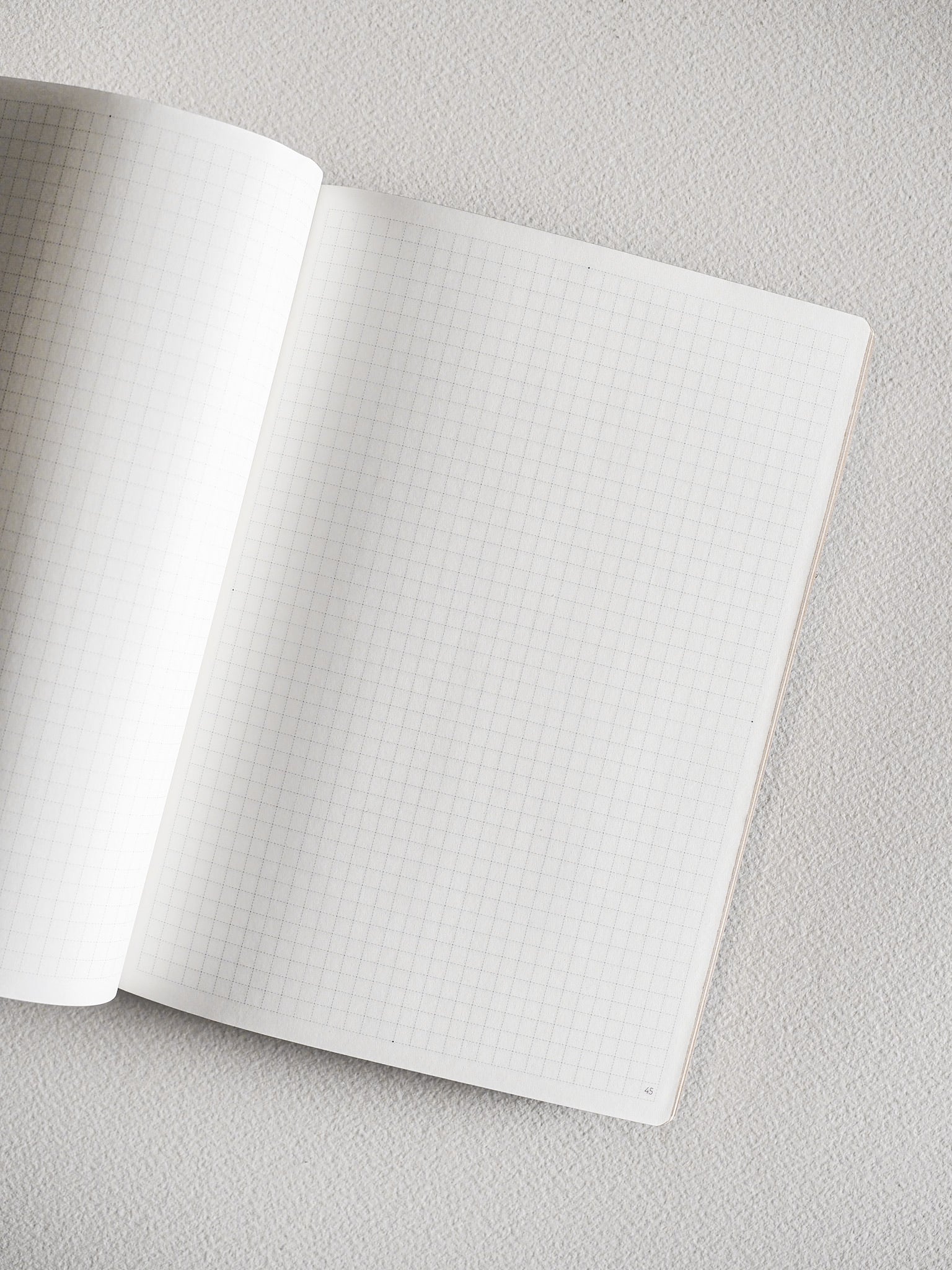 Open B6 grid notebook featuring structured, graph-patterned pages with light lines and printed page numbers, perfect for detailed planning and writing.