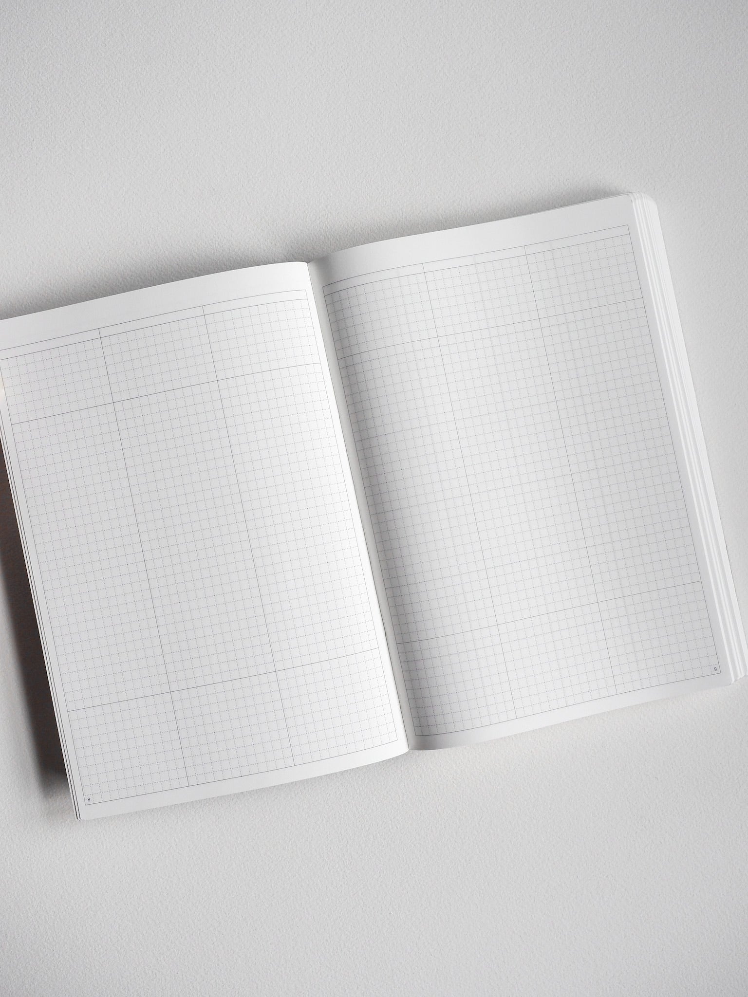 Open A5 undated planner showing two pages covered in faint light gray graph paper, ideal for organized daily note-taking and planning.