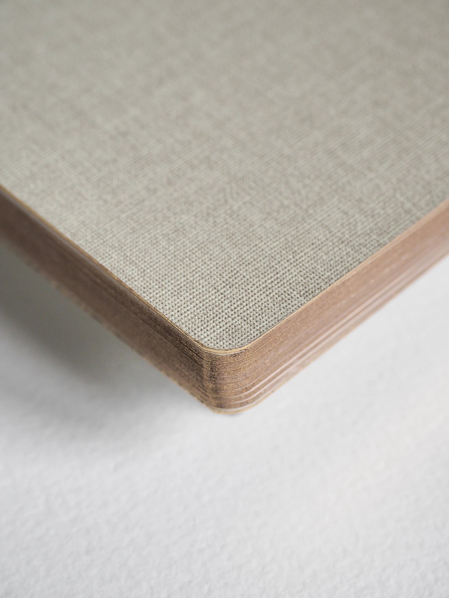 Close-up of a square panel corner showing a woven or textured light beige top surface with layered natural wood edges, photographed on a white background.
#Color_Linen