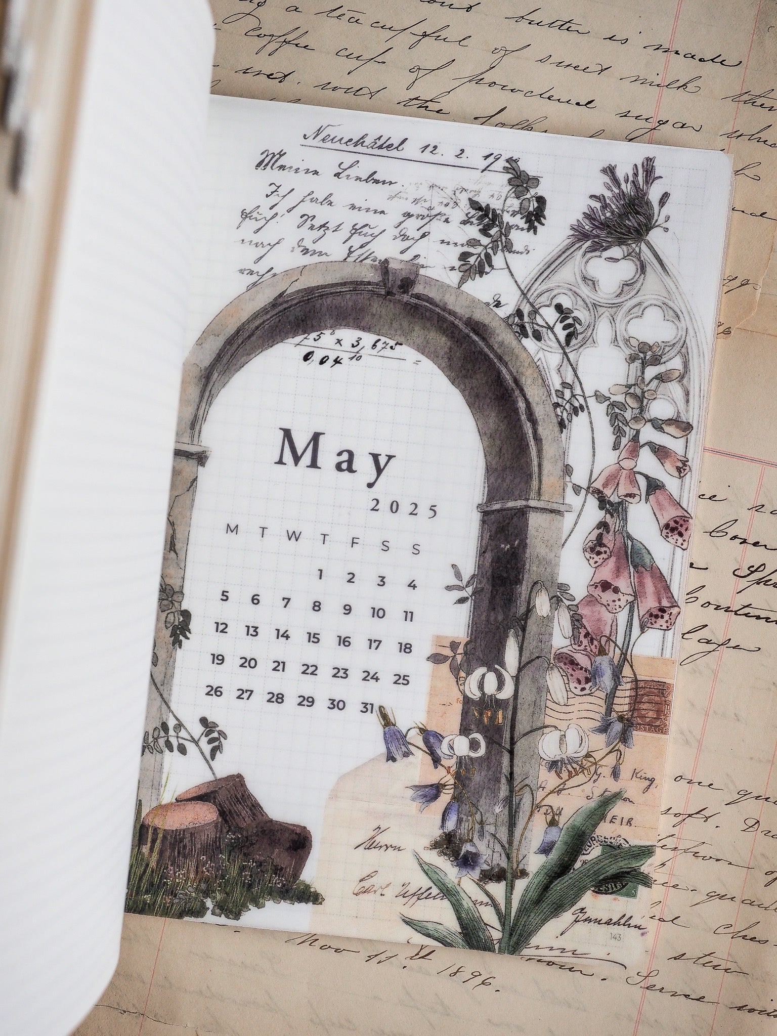 Decorative May 2025 monthly calendar featuring a rustic arched frame and lush botanical sketches of flowers and leaves for a vintage planner aesthetic.
