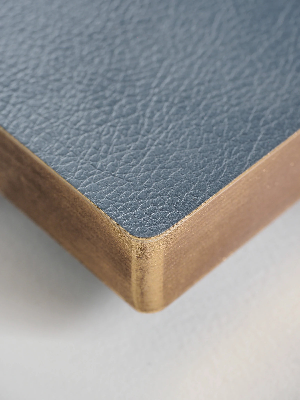 Close-up of a notebook corner showing a light blue textured cover and white page edges on a white background.
#Color_Mist