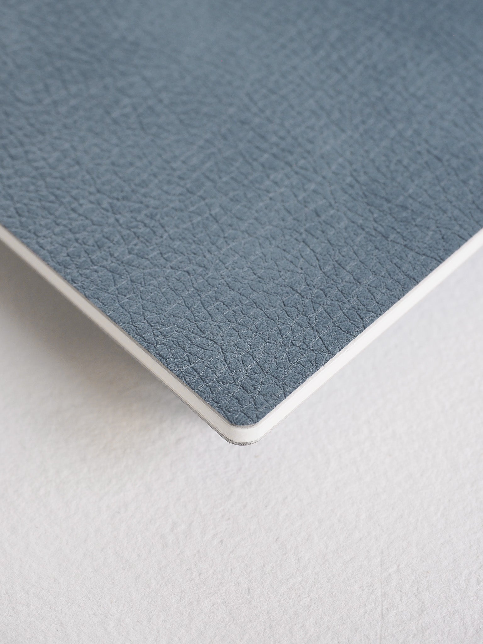 Durable charcoal gray booklet featuring a fine, pebbled faux leather texture, designed as a compact notebook for travel and correspondence.