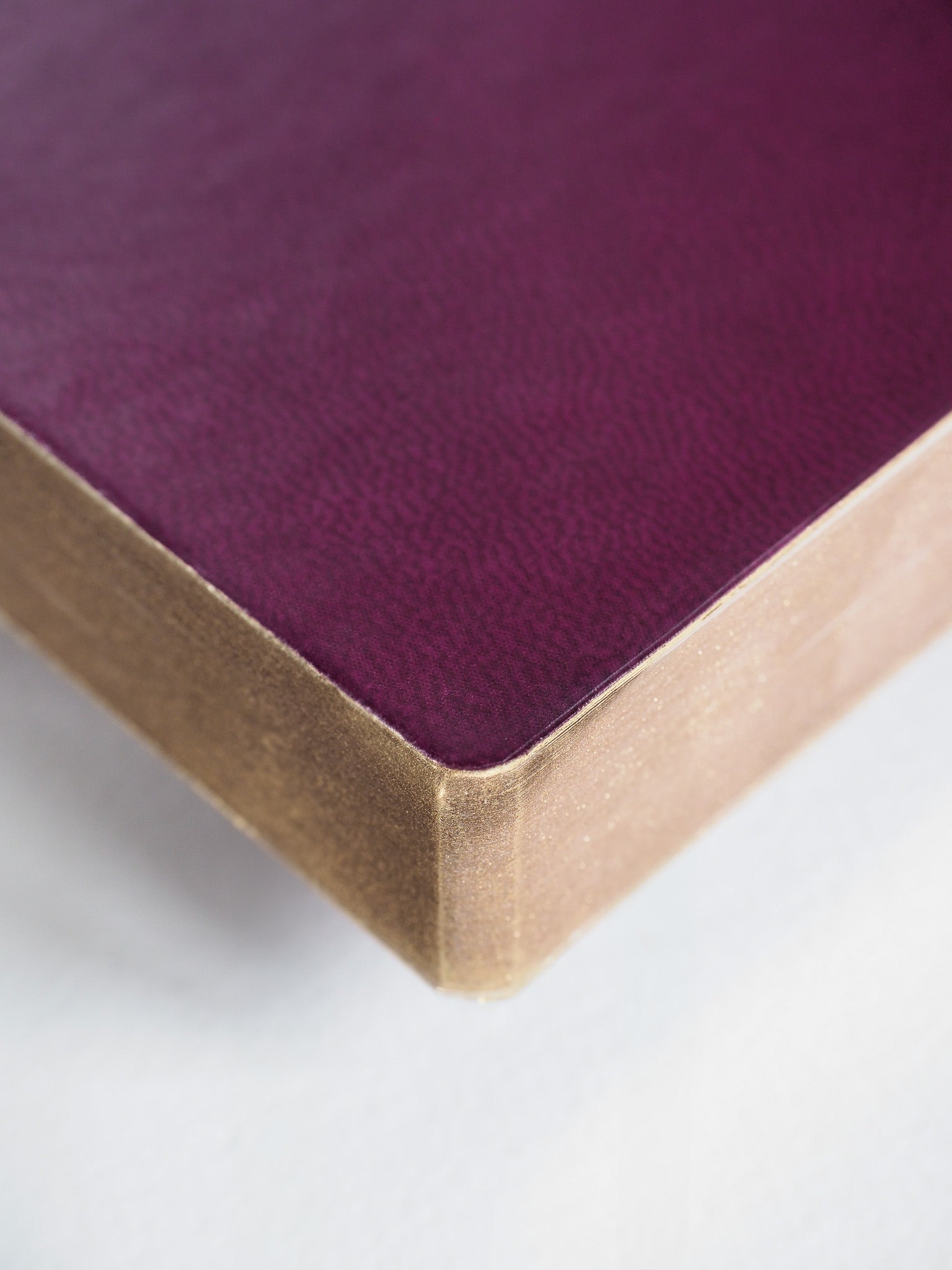 Deep plum A6 grid notebook featuring a subtly textured cover and light cream-colored binding edge, ready for organized planning.