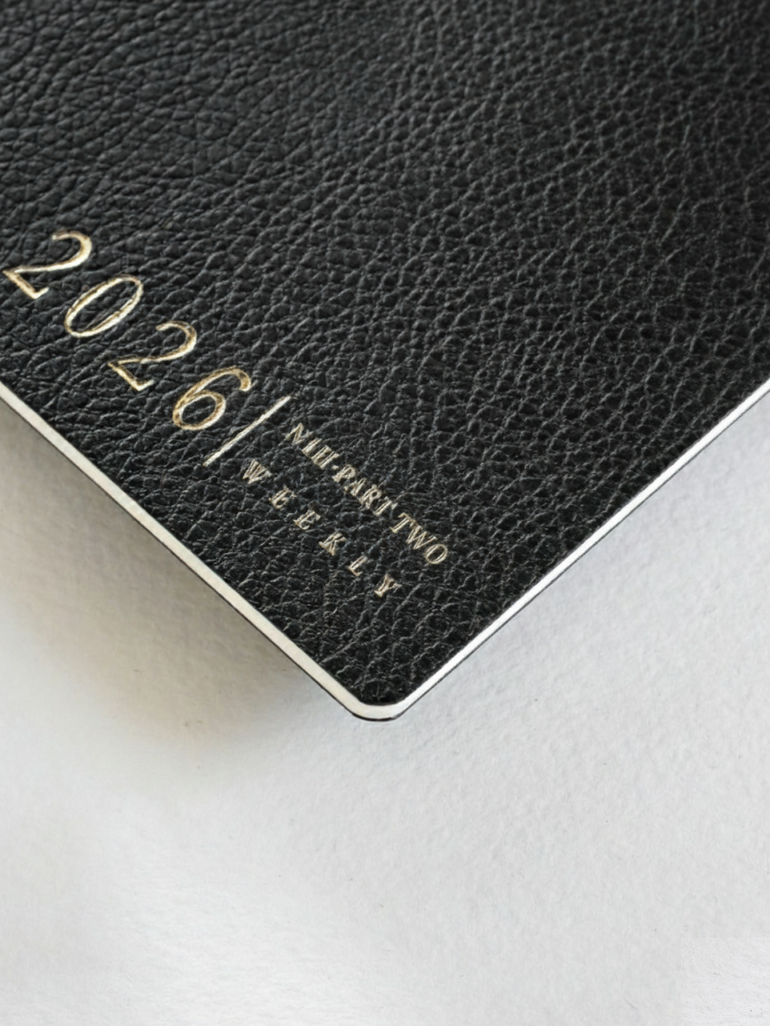 Dark, textured black booklet cover featuring gold foiled lettering that reads "2026 / NAI PART TWO WEEKLY."