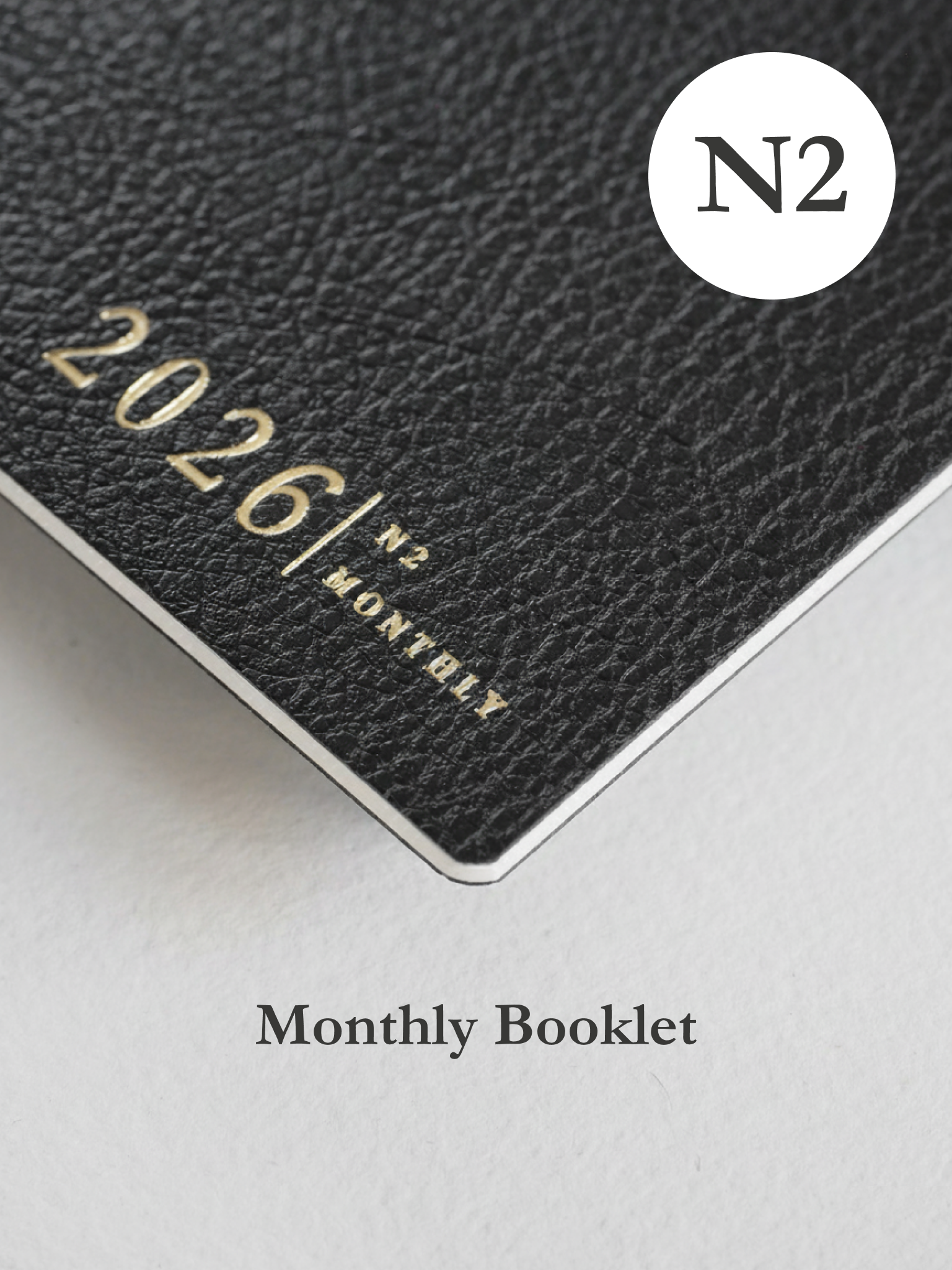 Dark, textured monthly planner booklet displaying "2026/ N2 MONTHLY" in elegant gold lettering.