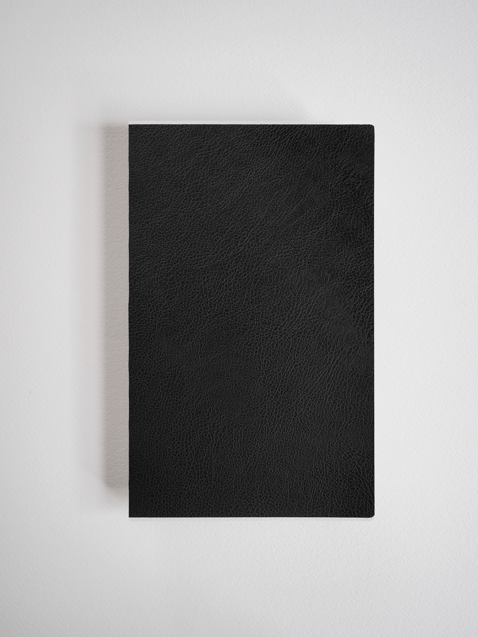 Minimalist A5 slim notebook featuring a deep black, textured faux-leather cover, ideal for journaling or professional use.