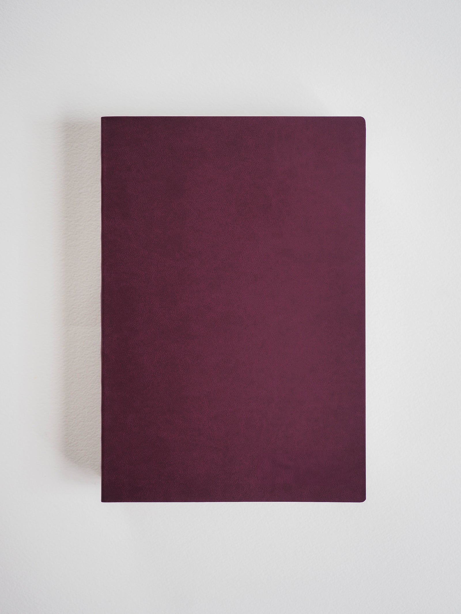 Plain A5 notebook with a smooth, matte, deep burgundy faux leather cover, perfect for journaling or structured note-taking.