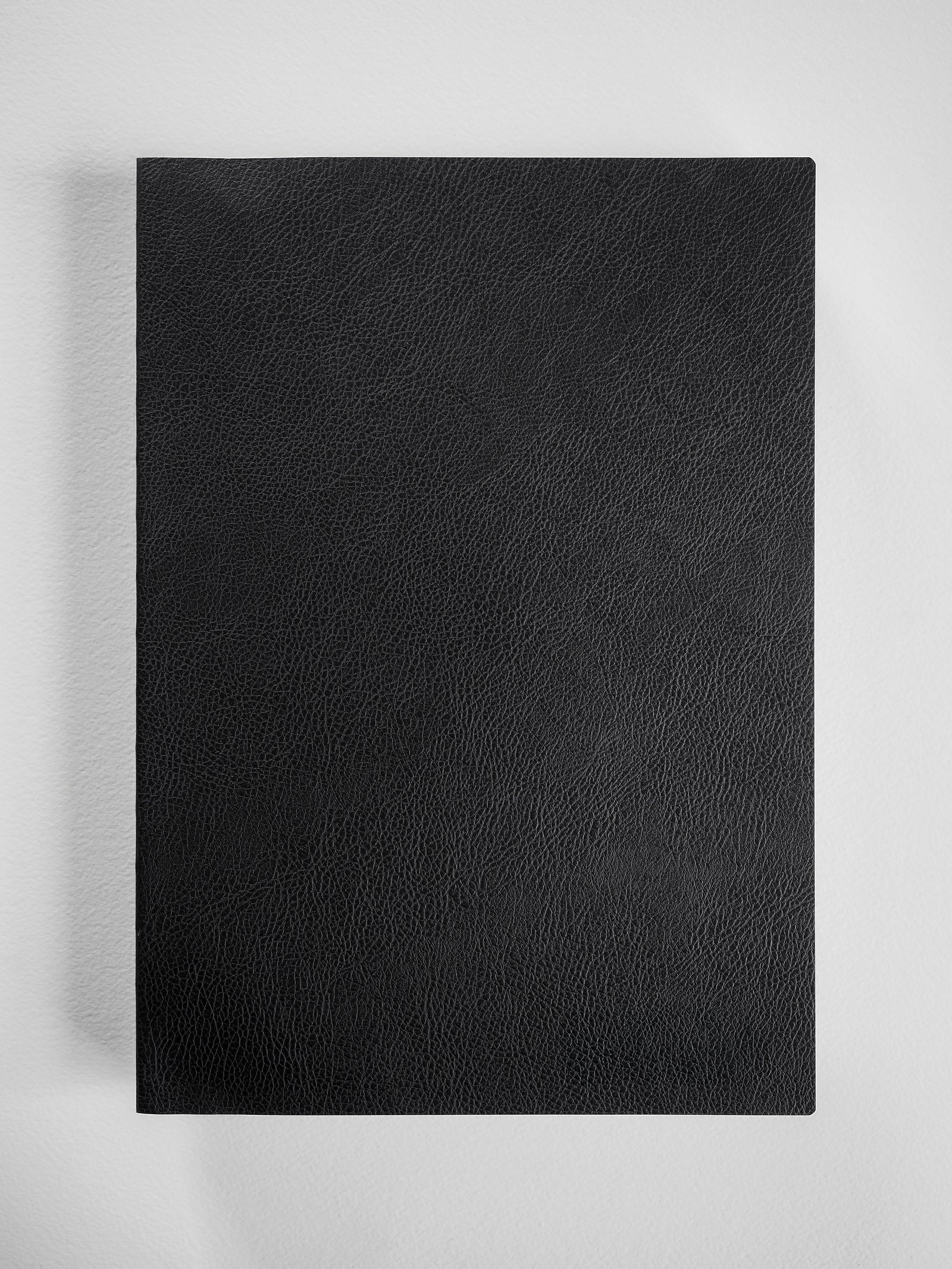 Deep matte black notebook cover featuring a finely textured, professional faux leather finish suitable for comprehensive grid planning.