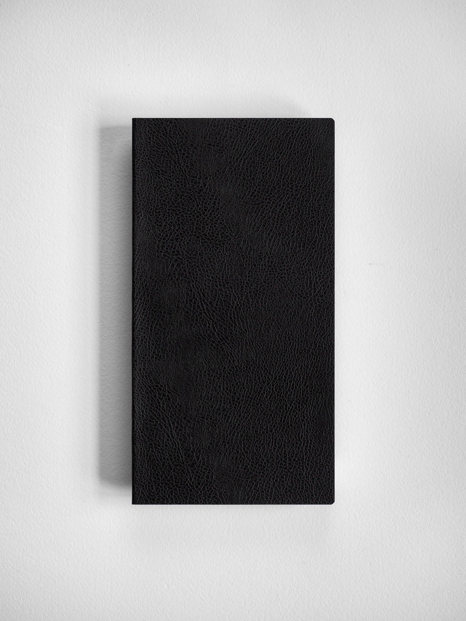 Sleek black notebook with a deep pebbled texture, ideal for writing and structured grid planning.
