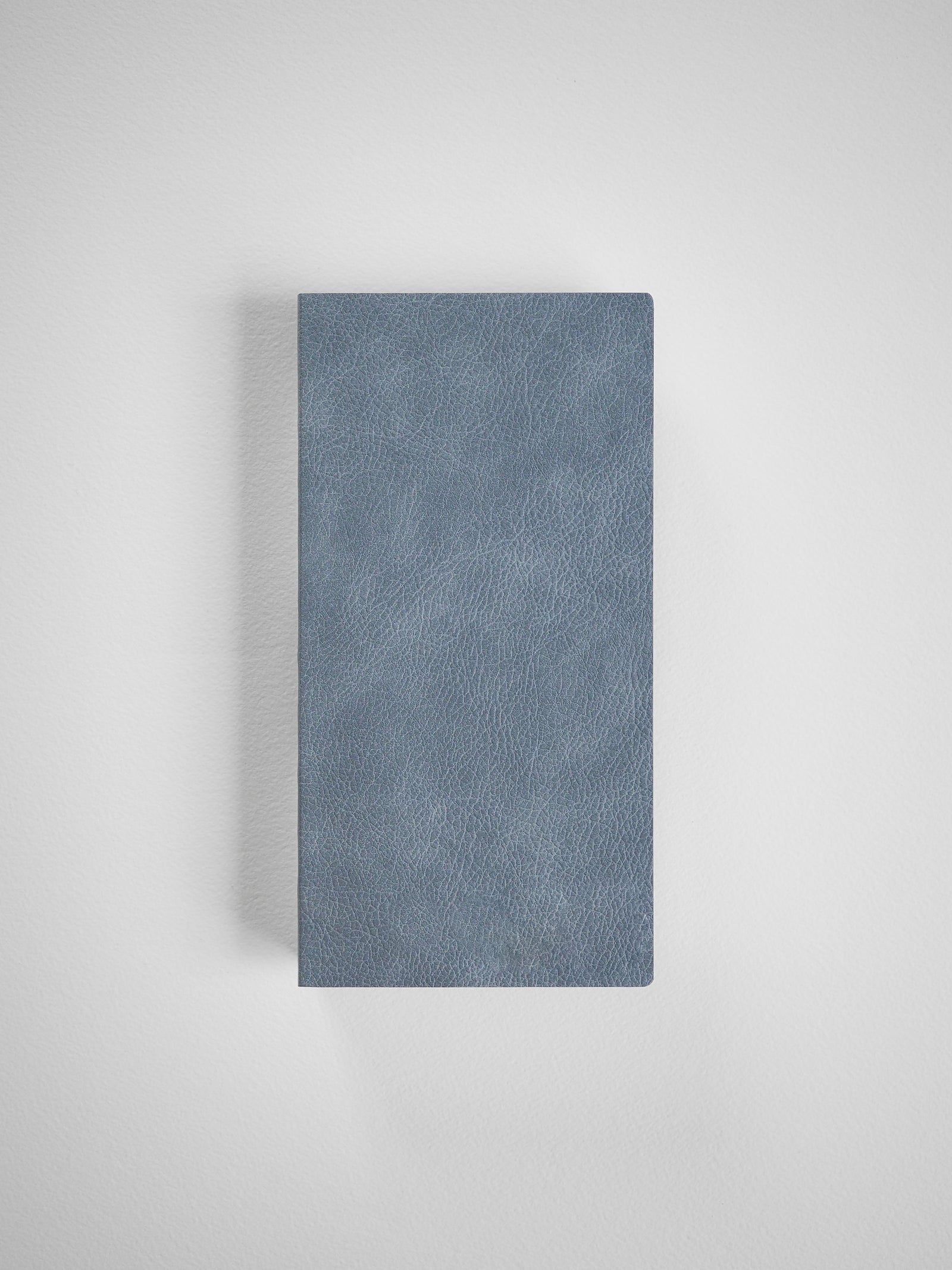 Matte dusty blue grid notebook with a textured faux leather cover, ideal for structured planning, writing, and organized weekly notes.