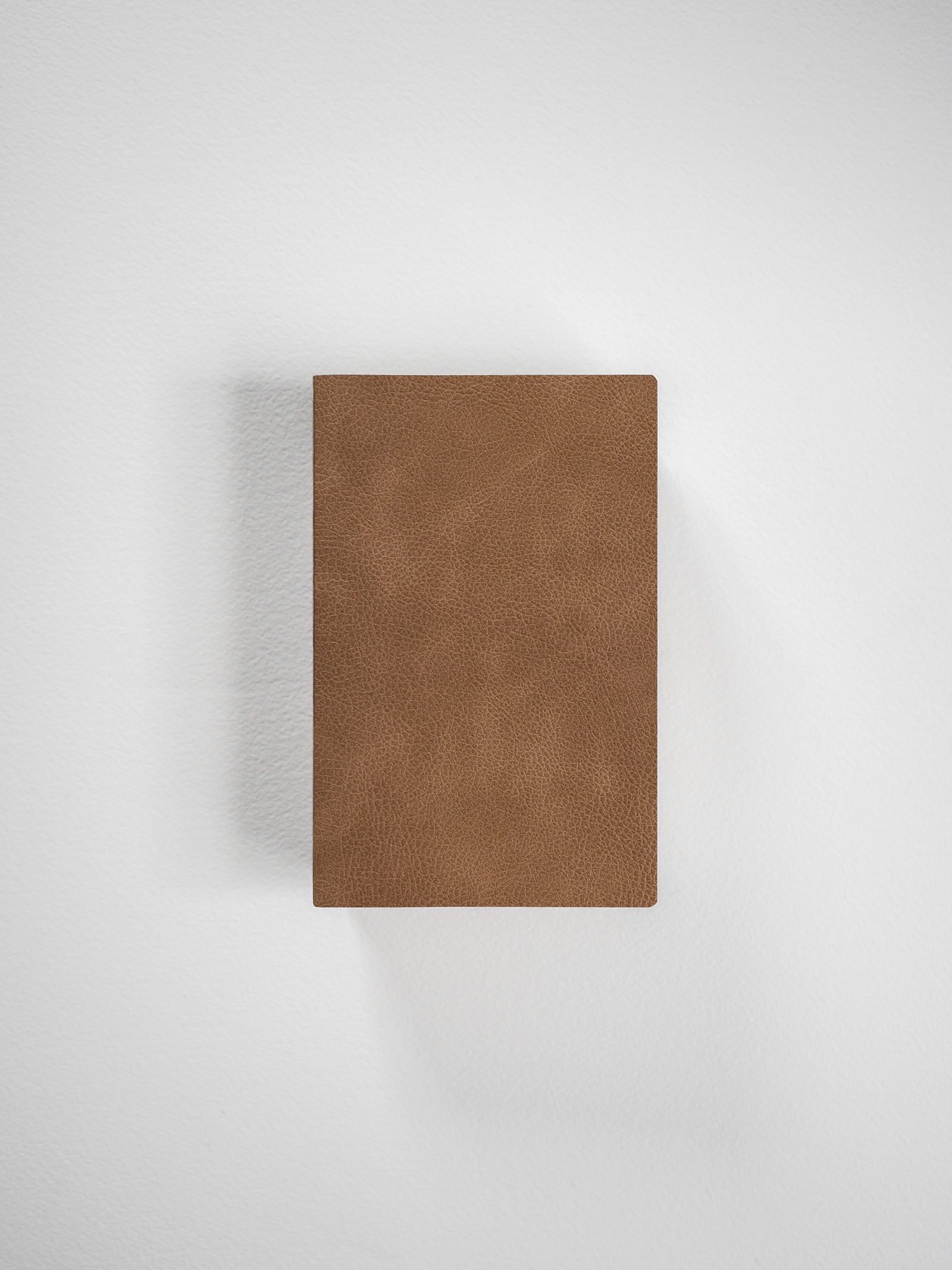 Portable grid notebook bound with a solid, medium brown faux leather cover, designed for everyday writing and planning.