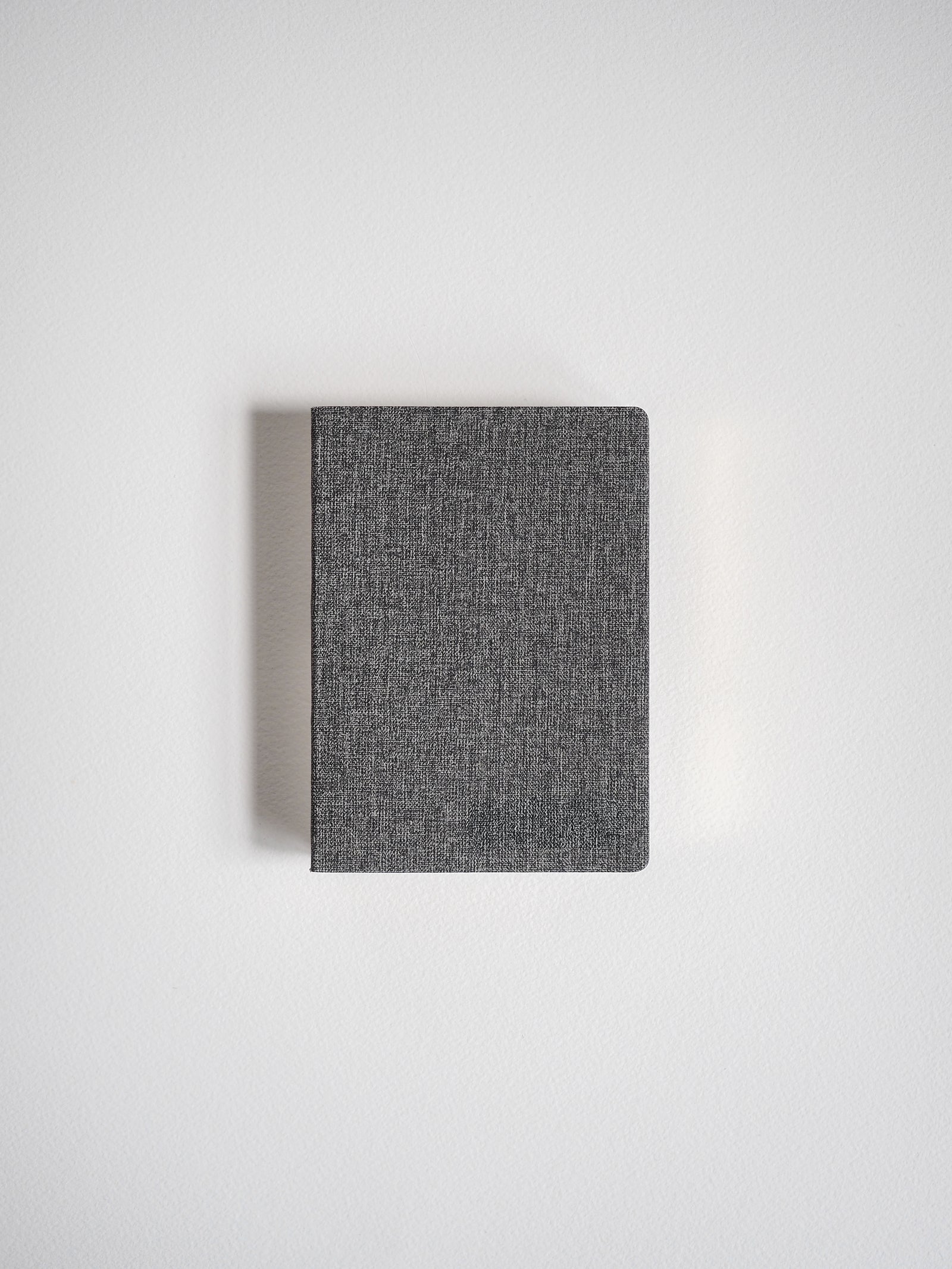 Portable grid notebook featuring a dark, heathered charcoal grey textured cover for everyday writing.