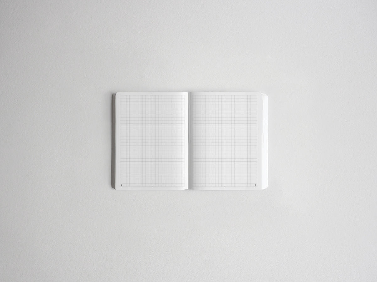 An open white notebook with light gray grid paper pages, centered on a clean white background.