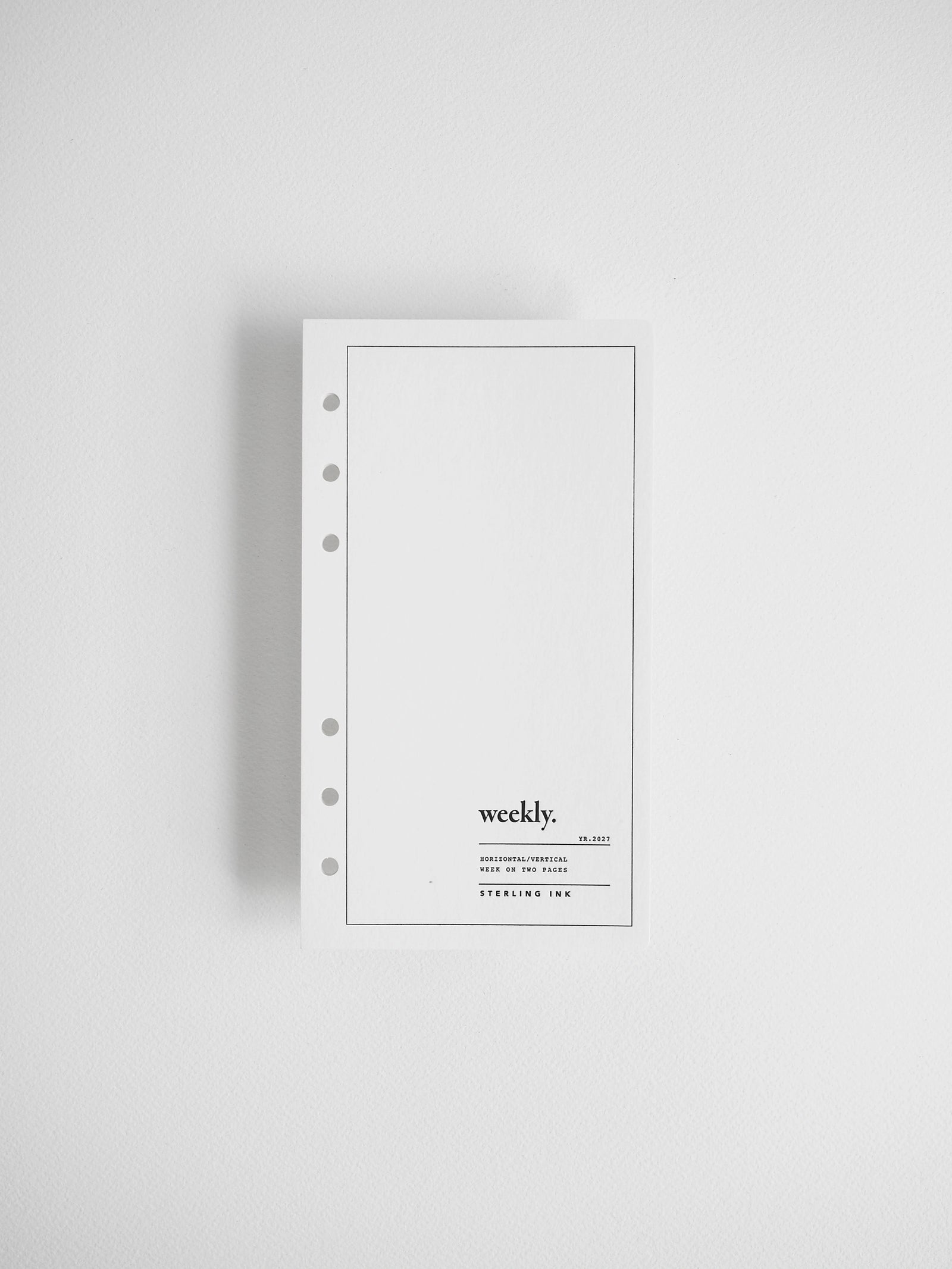 A minimalist white weekly binder ring notepad with a single ring hole on the left side, featuring the brand name 'weekly.' printed near the bottom, shown against a clean white background.
#Size_Personal