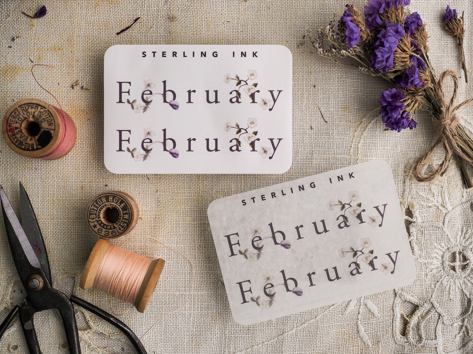 Botanical February month sticker featuring delicate purple floral accents and "Sterling Ink" text, perfect for decorative journaling and planner scrapbooking.