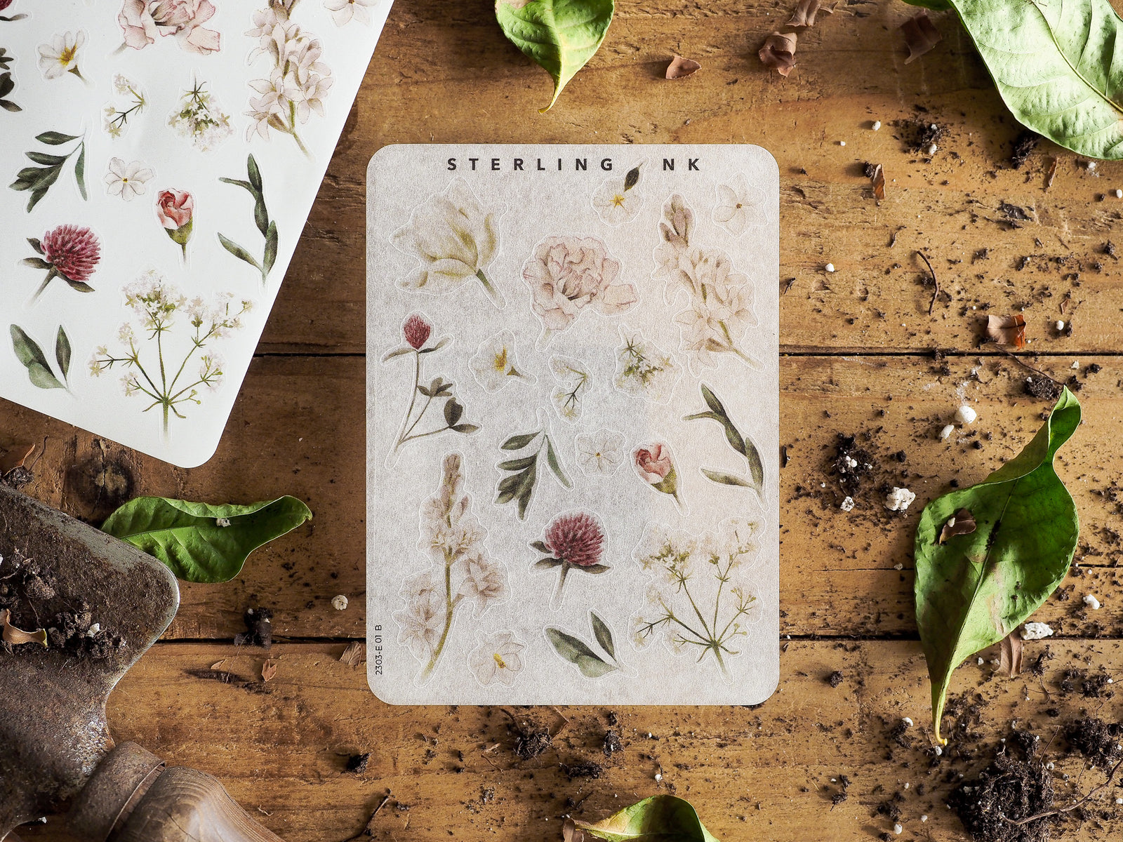 Pale, detailed sticker sheet featuring a collection of delicate botanical illustrations, including soft pink and white blossoms and lush greenery.