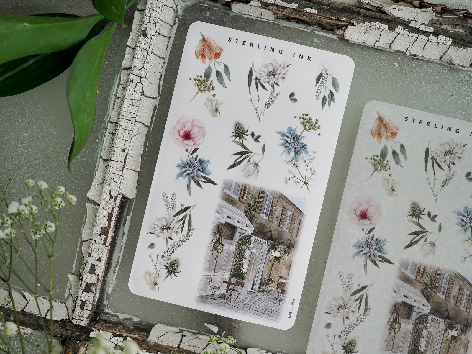 Sticker sheet featuring botanical watercolors of pink and blue flowers alongside a rustic photo of a European building, perfect for crafting May 2023 arrangements.