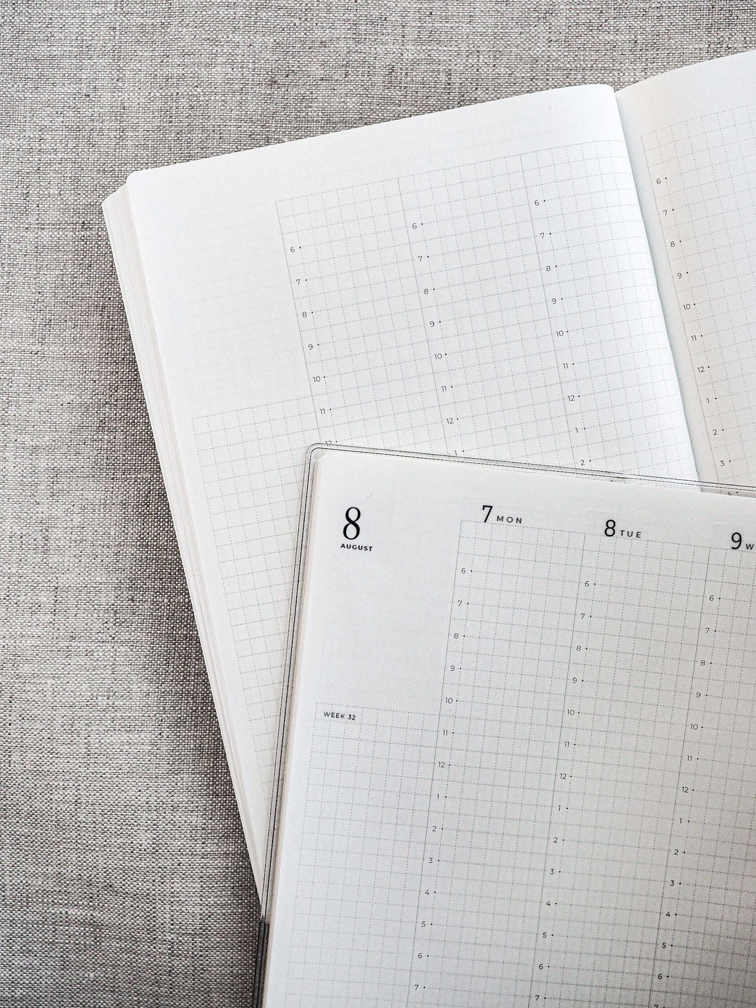 Open spiral planner pages displaying structured weekly and monthly grids, ready for customizable planning and scheduling using date stickers.