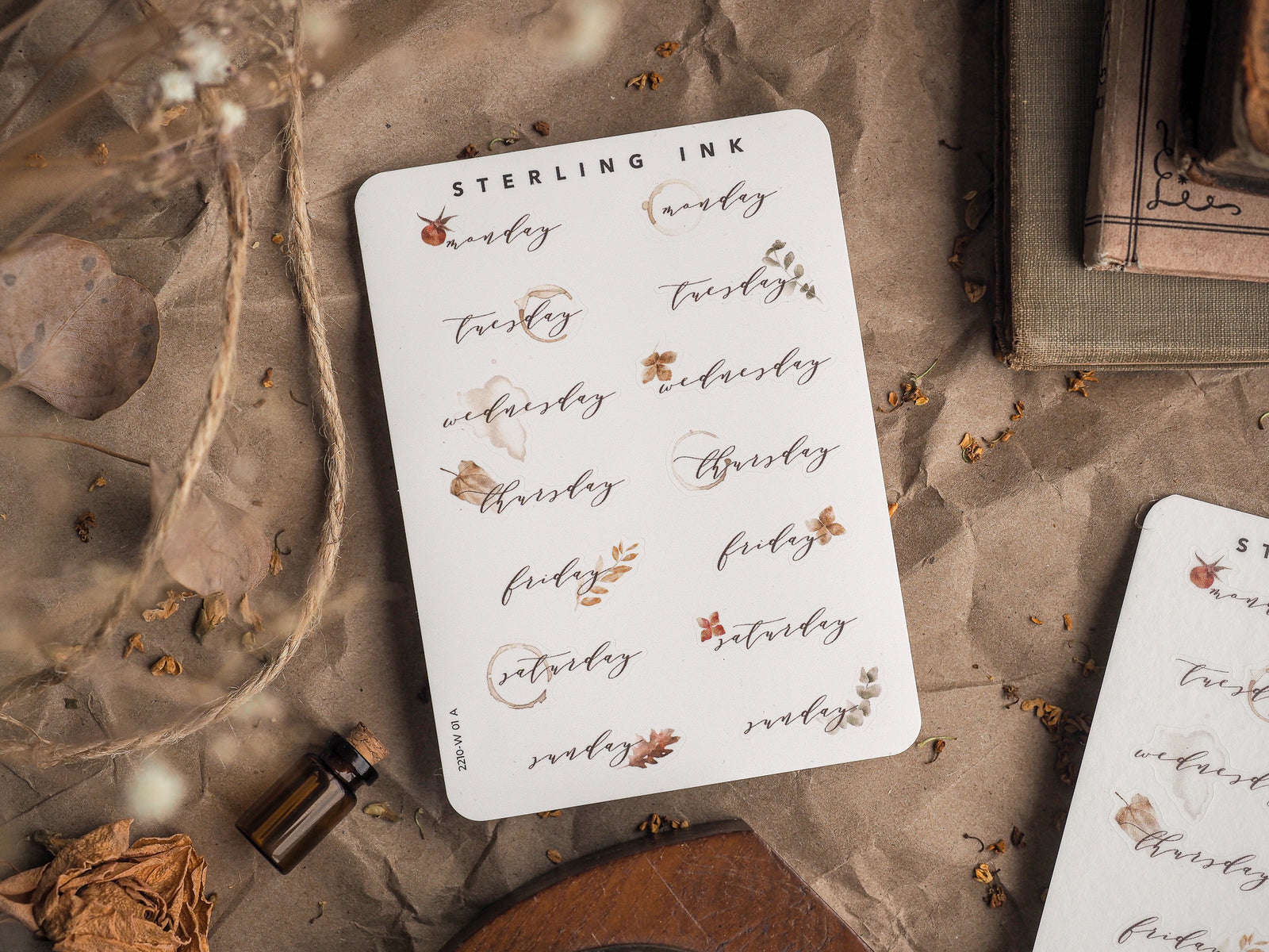 Elegant white sticker set labeling weekdays (Monday through Sunday) with minimalist script text and delicate sepia-toned floral accents.