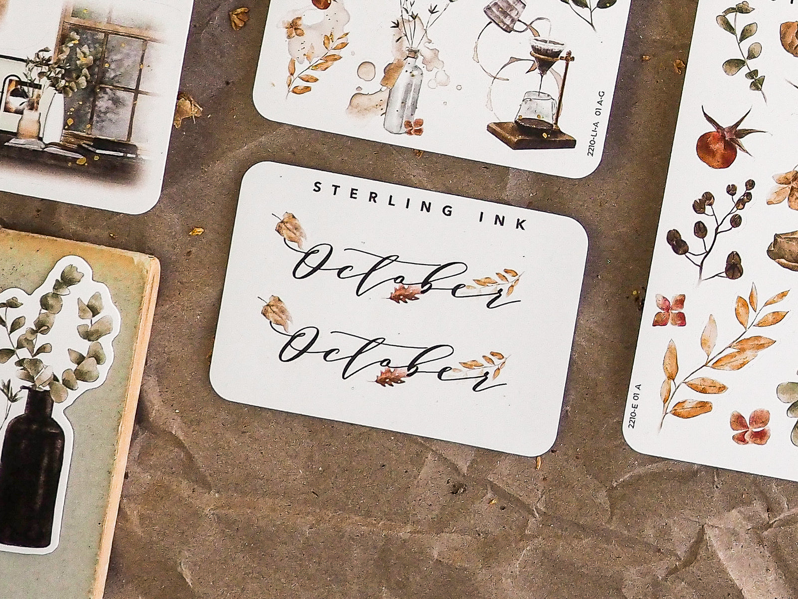 Autumn-themed sticker featuring the word "October" in elegant script calligraphy, surrounded by rustic watercolor fall foliage and delicate leaves.