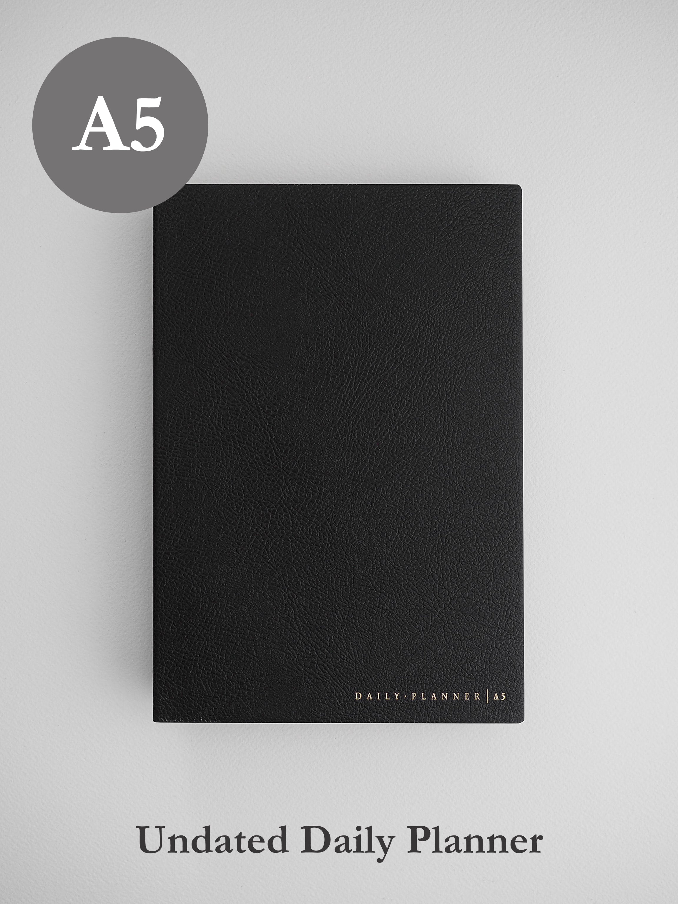 Minimalist black A5 undated daily planner journal featuring a sleek, matte cover and subtly branded with "Daily Planner | A5" at the bottom.