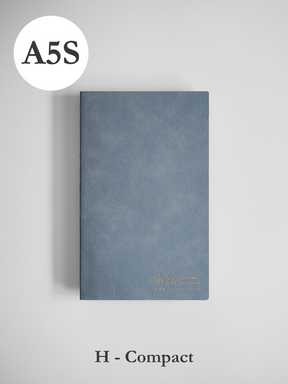 Compact A5 planner bound in slate blue faux leather, subtly embossed with the year 2026 in metallic gold lettering.