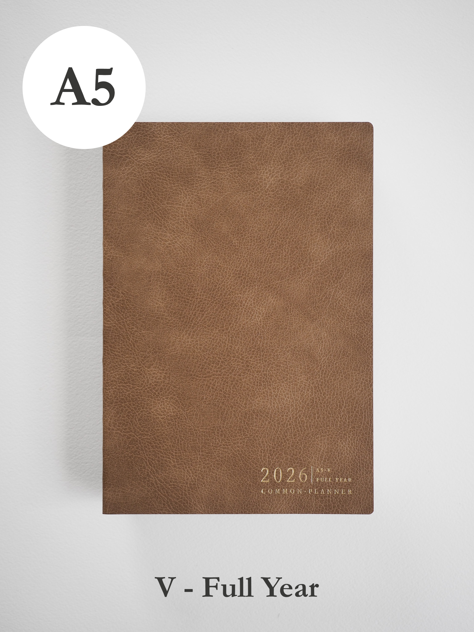 A minimalist A5 planner cover in a rich, earthy tan tone, featuring centered embossed text that reads "2026 Full Year Common Planner."