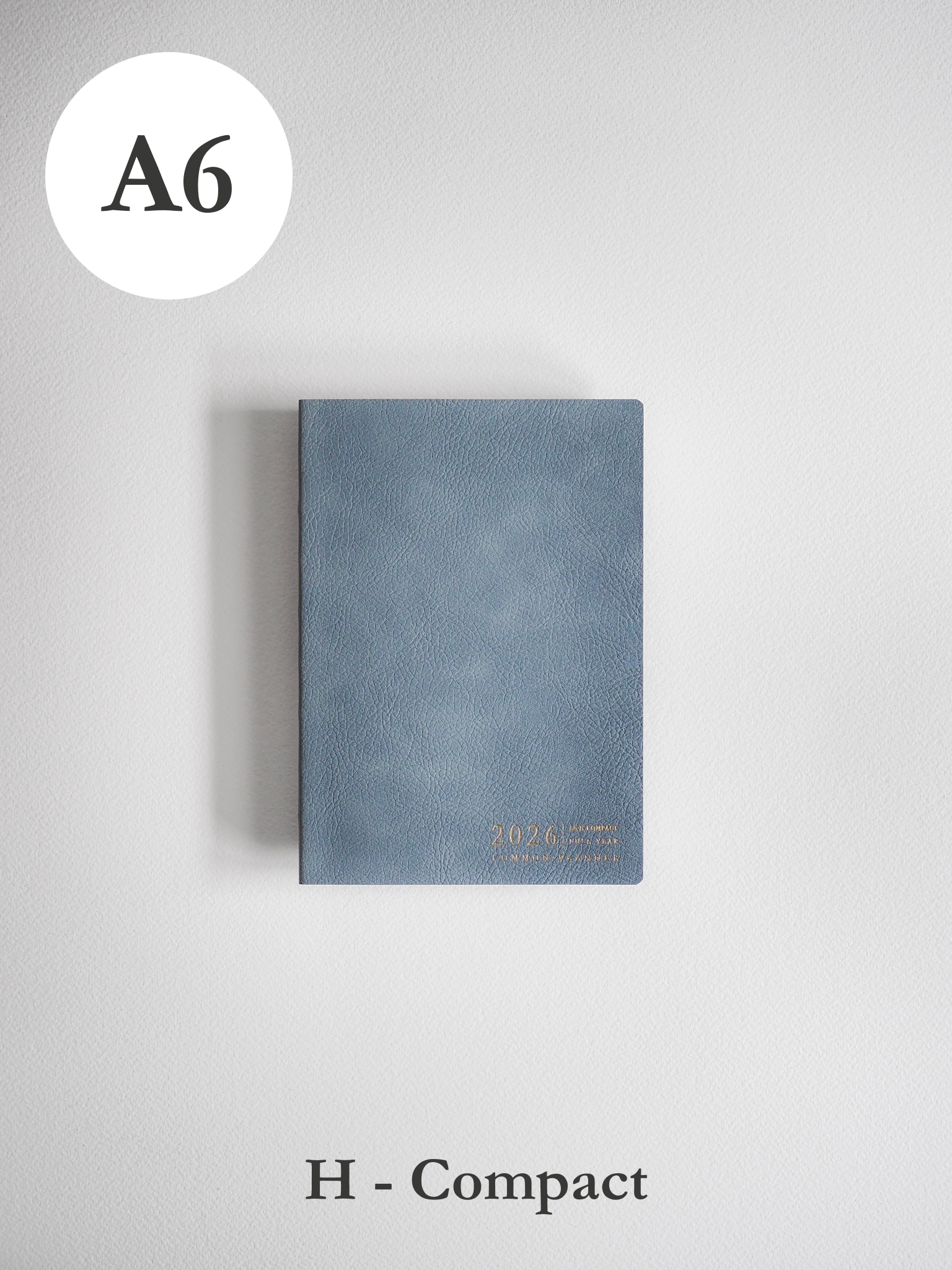 Textured slate blue A6 compact planner featuring elegant gold foil accents and the embossed year 2026 on the durable cover.