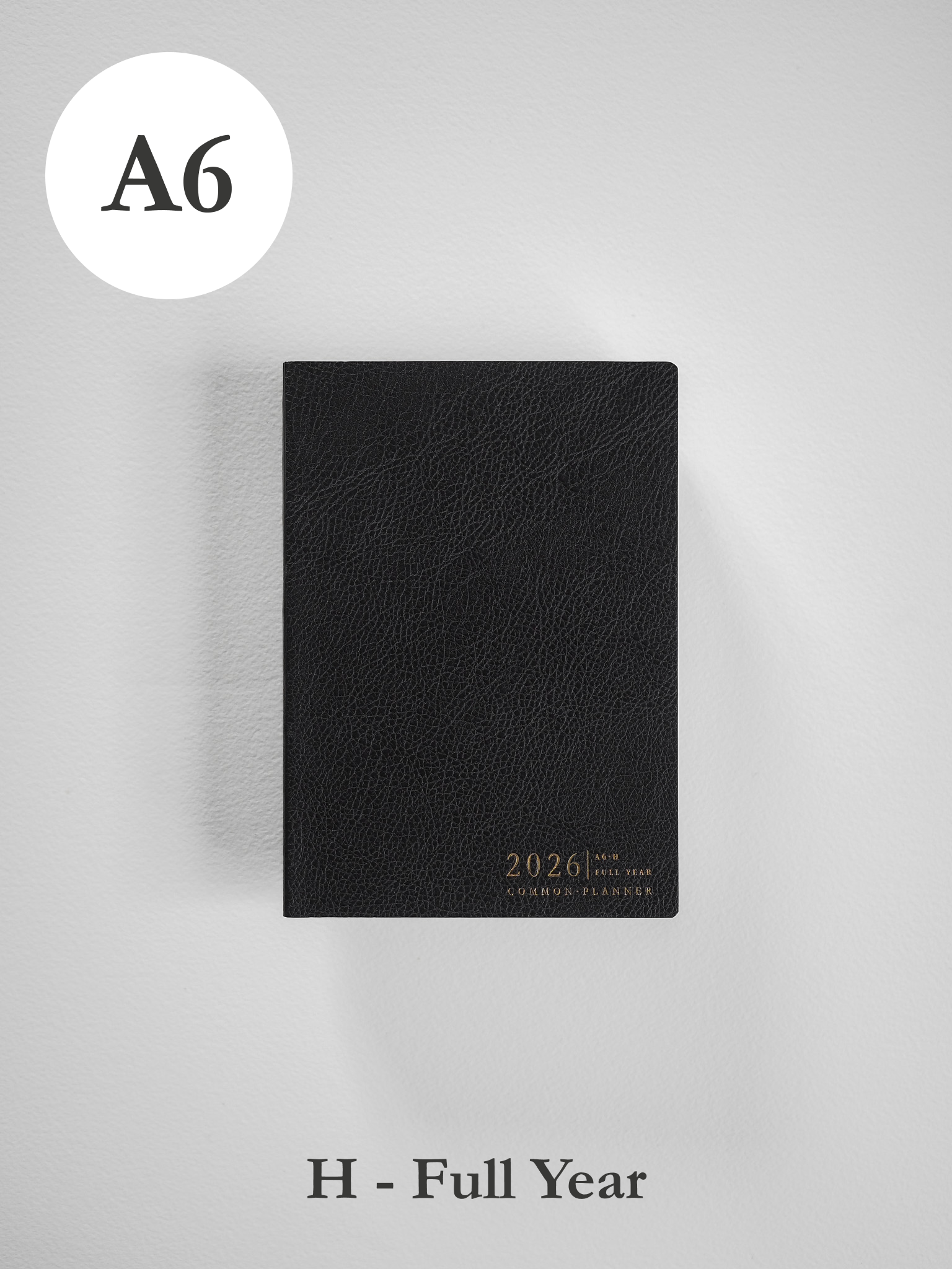 Minimalist black A6 planner cover with a subtle textured finish, featuring embossed gold text for "2026" and "Common Planner."