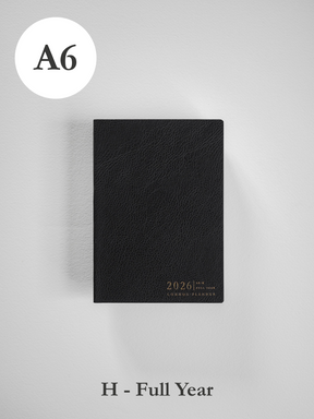 Minimalist black A6 planner cover with a subtle textured finish, featuring embossed gold text for "2026" and "Common Planner."