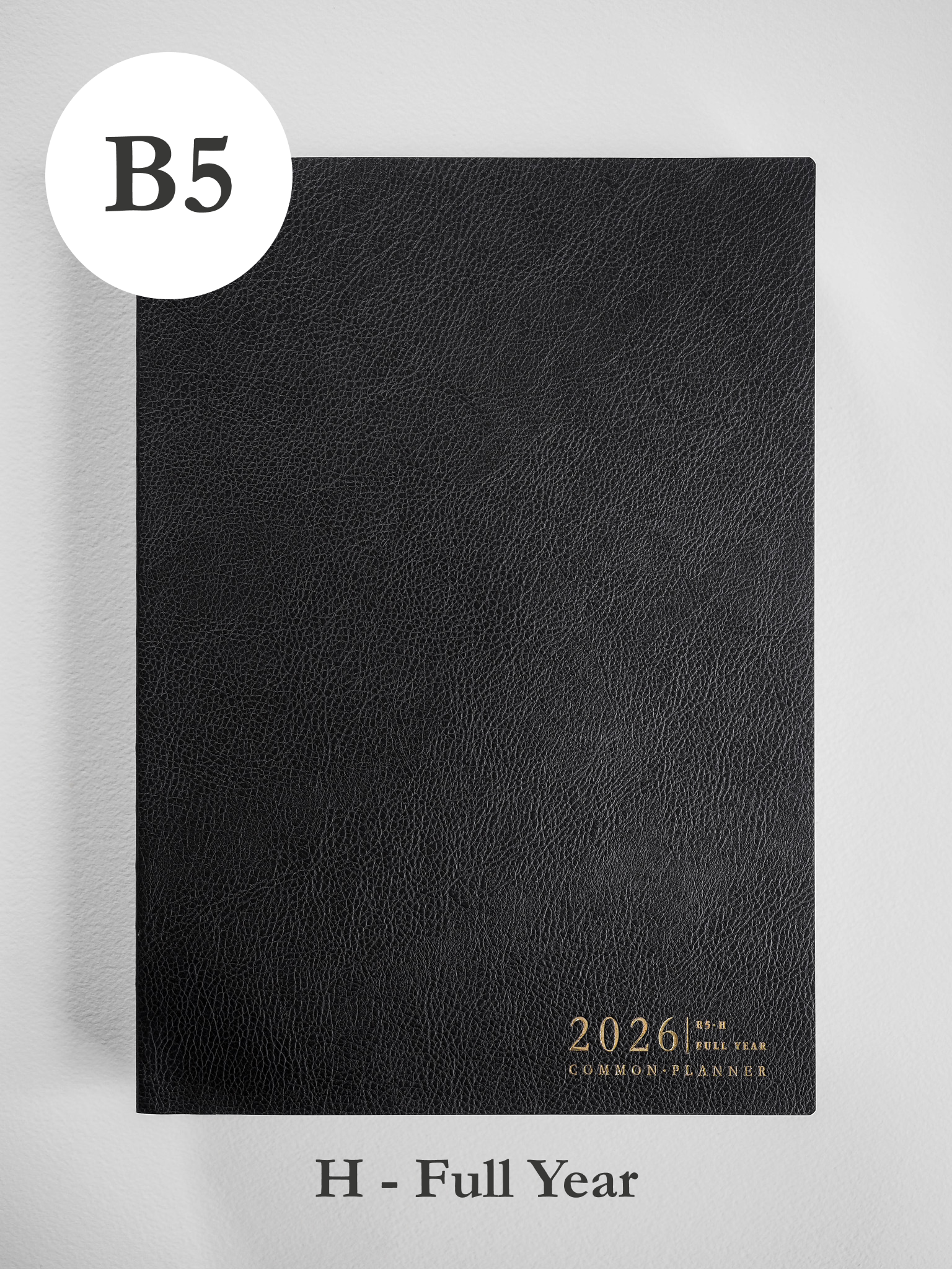 Black, textured B5 planner cover featuring foiled gold text centered at the bottom that reads "2026 Common Planner."