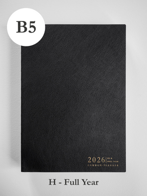 Black, textured B5 planner cover featuring foiled gold text centered at the bottom that reads "2026 Common Planner."