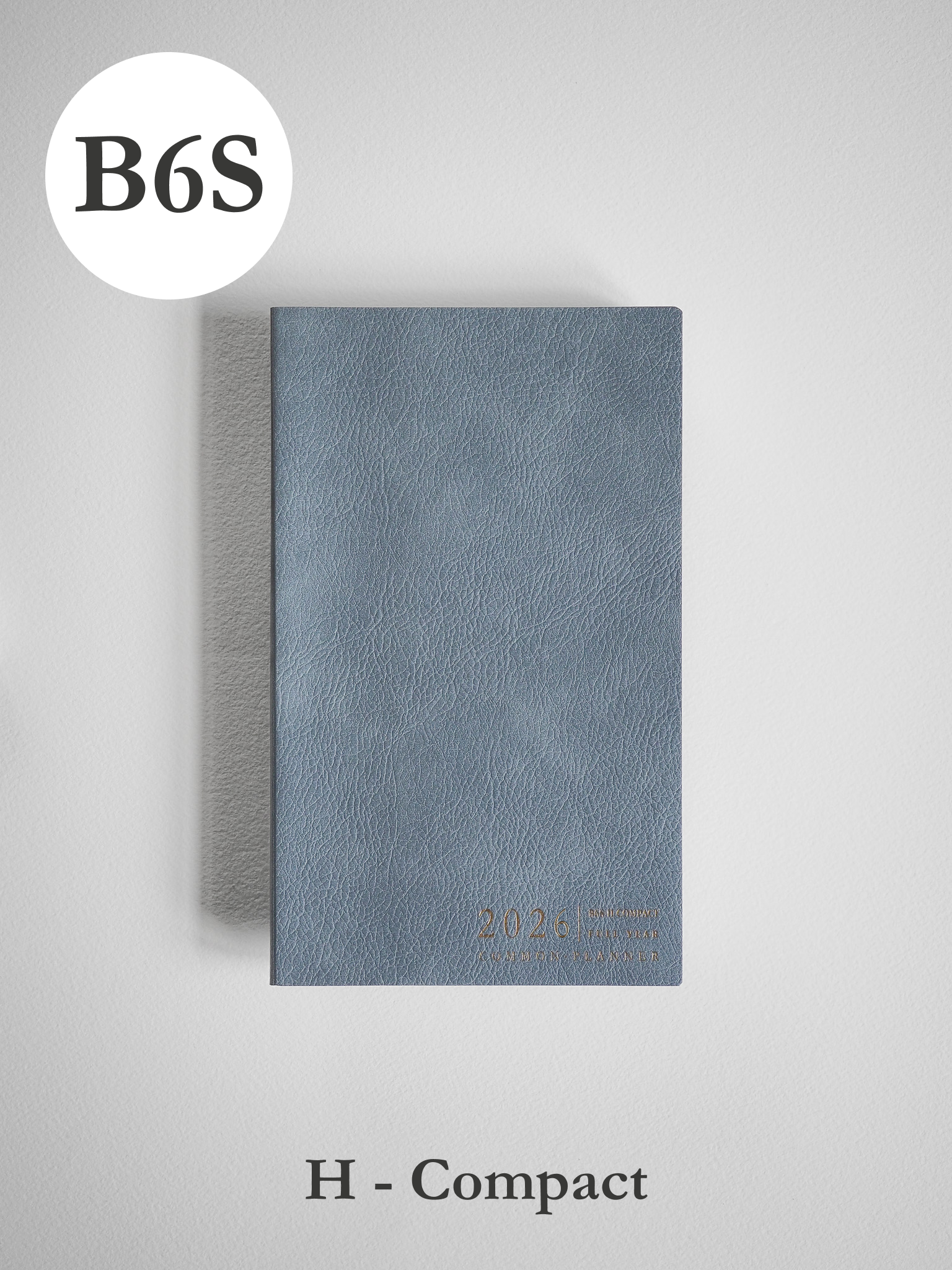 Minimalist B6 compact planner featuring a textured slate-blue cover and discreet embossed year markings for 2026 organization.