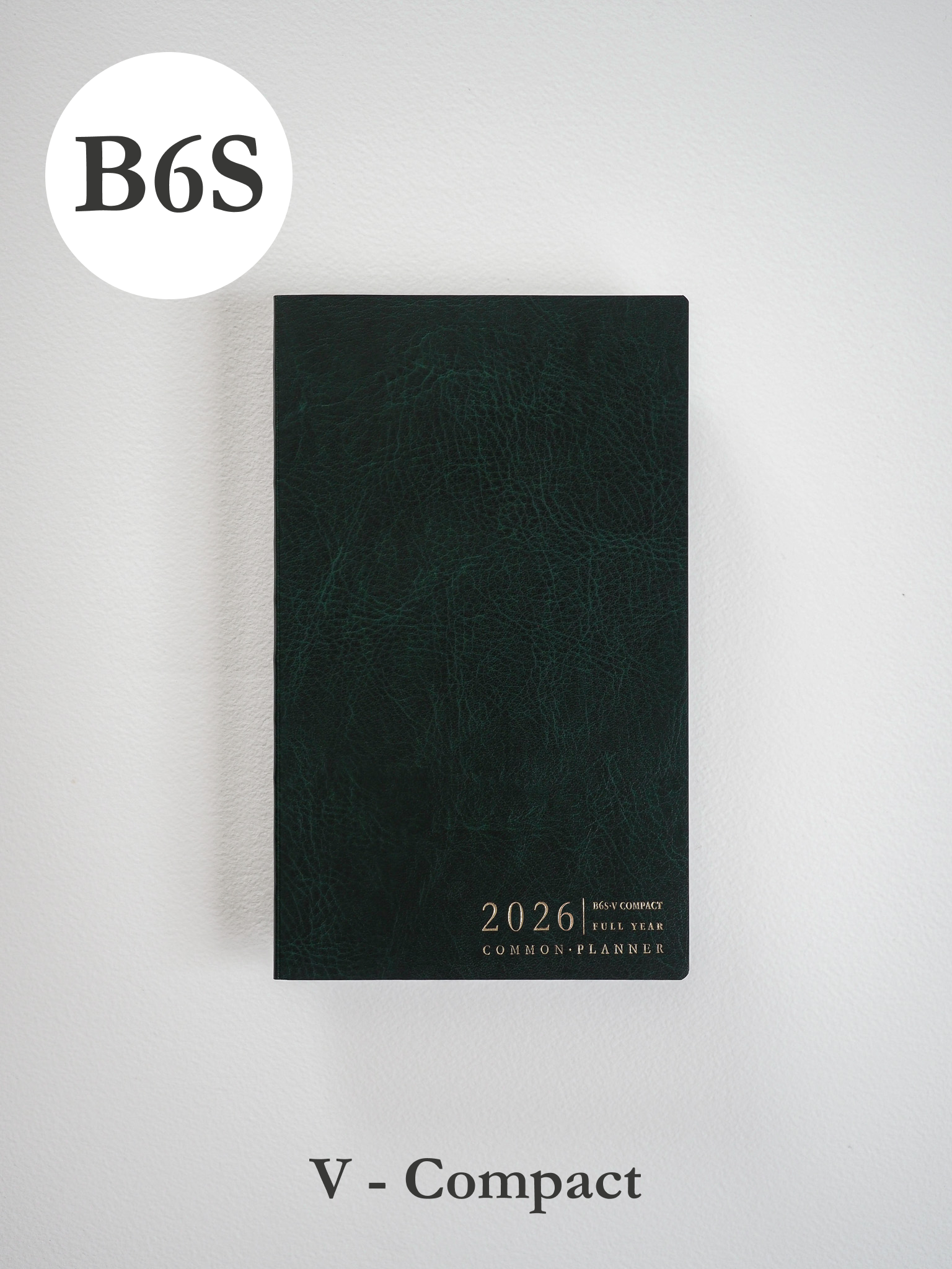 Deep, textured dark green planner cover with minimalist metallic typography centered on the front, displaying "2026 B6 Slim Compact Full Year Common Planner."