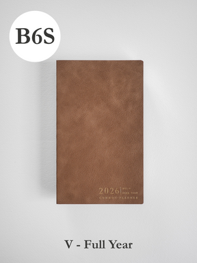 Minimalist B6 vertical planner in deep brown faux leather, subtly embossed with "2026" and the "Common Planner" title.
