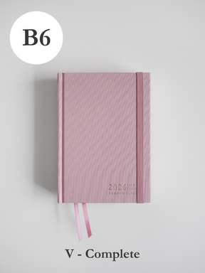 Soft dusty rose B6 common planner for 2026, featuring a subtle ribbed cover design, elastic closure, and attached matching pink ribbon bookmarks.